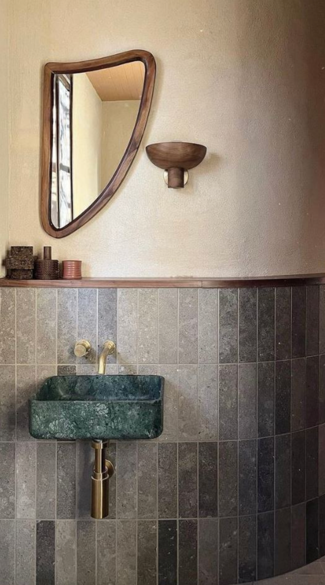 Bathroom with green marble sink, wooden shelf, and triangular mirror.
