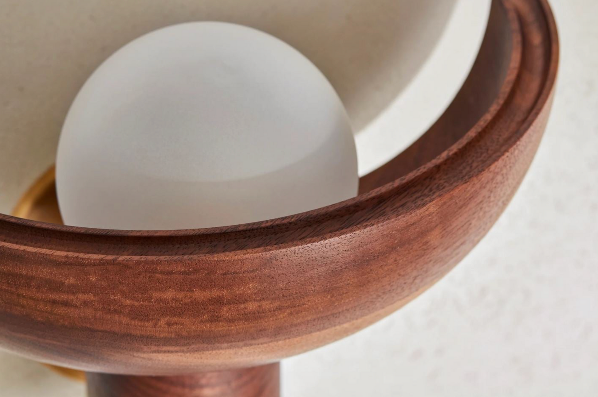 Wooden bowl with a white sphere inside on a neutral background