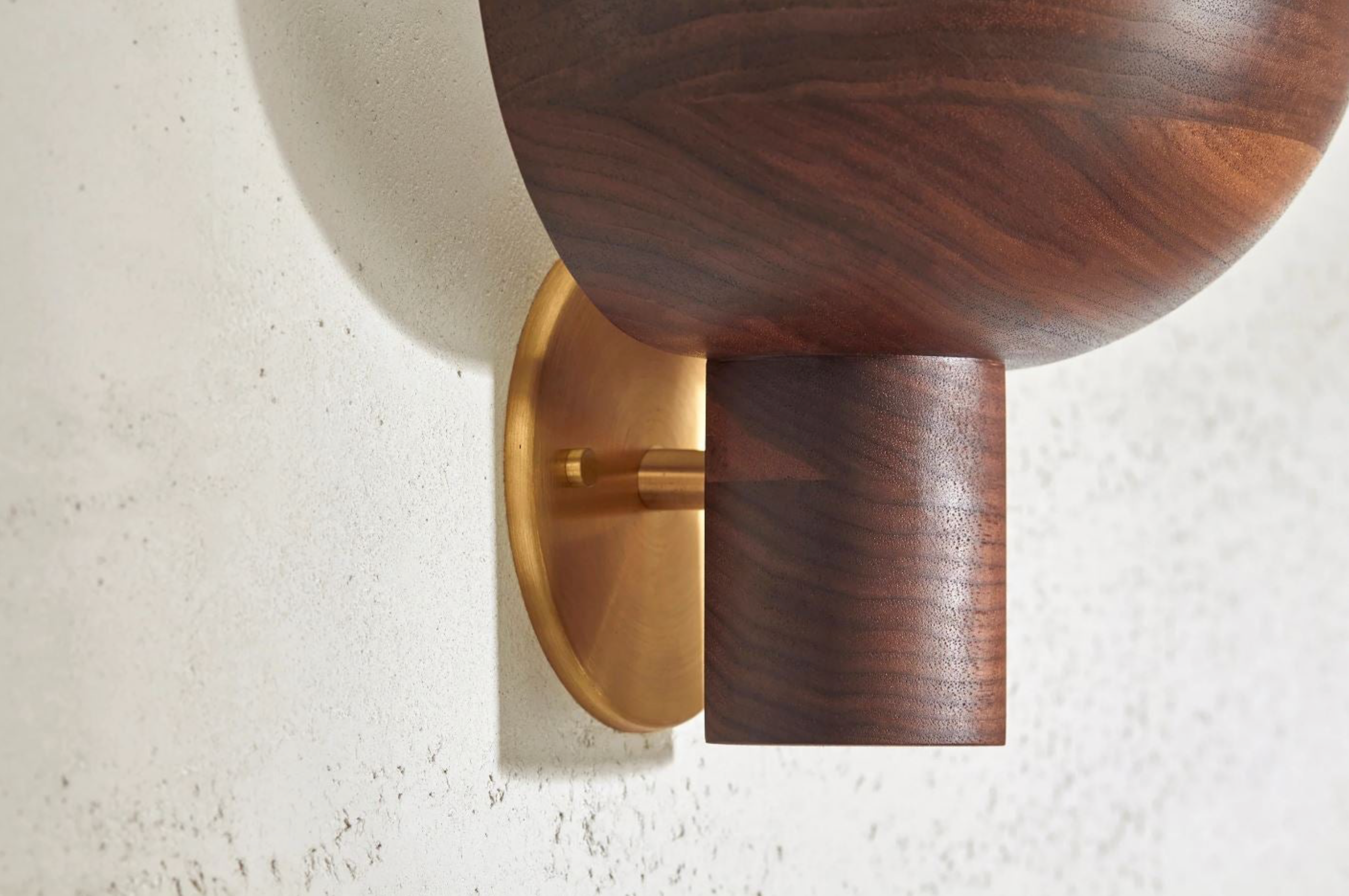 Wooden wall sconce with gold fixture on a light gray wall