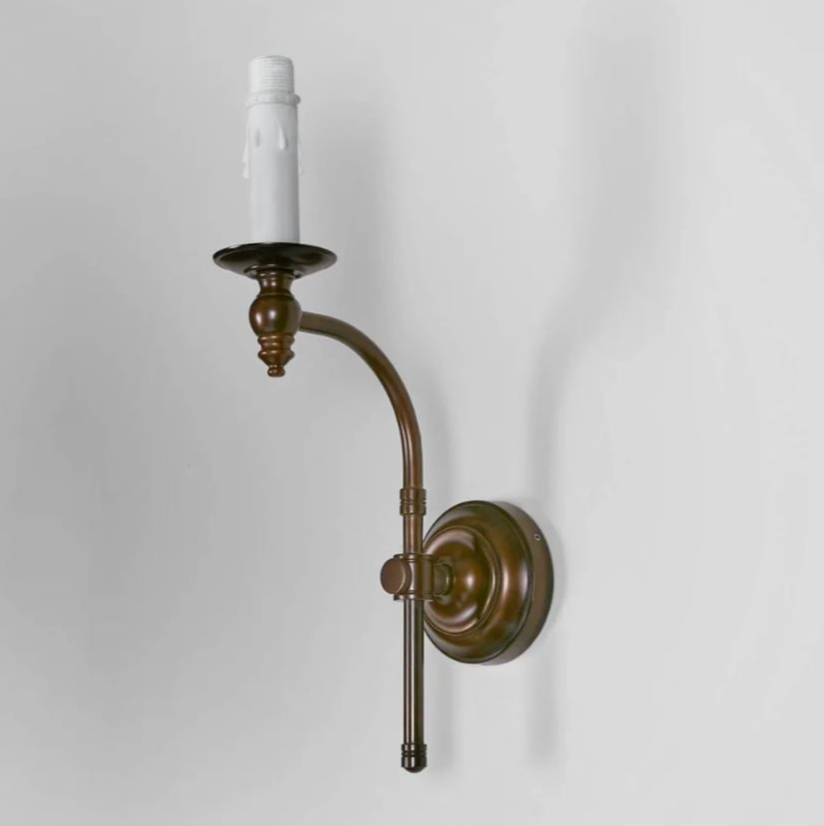 Bronze wall sconce with a white candle on a light gray background