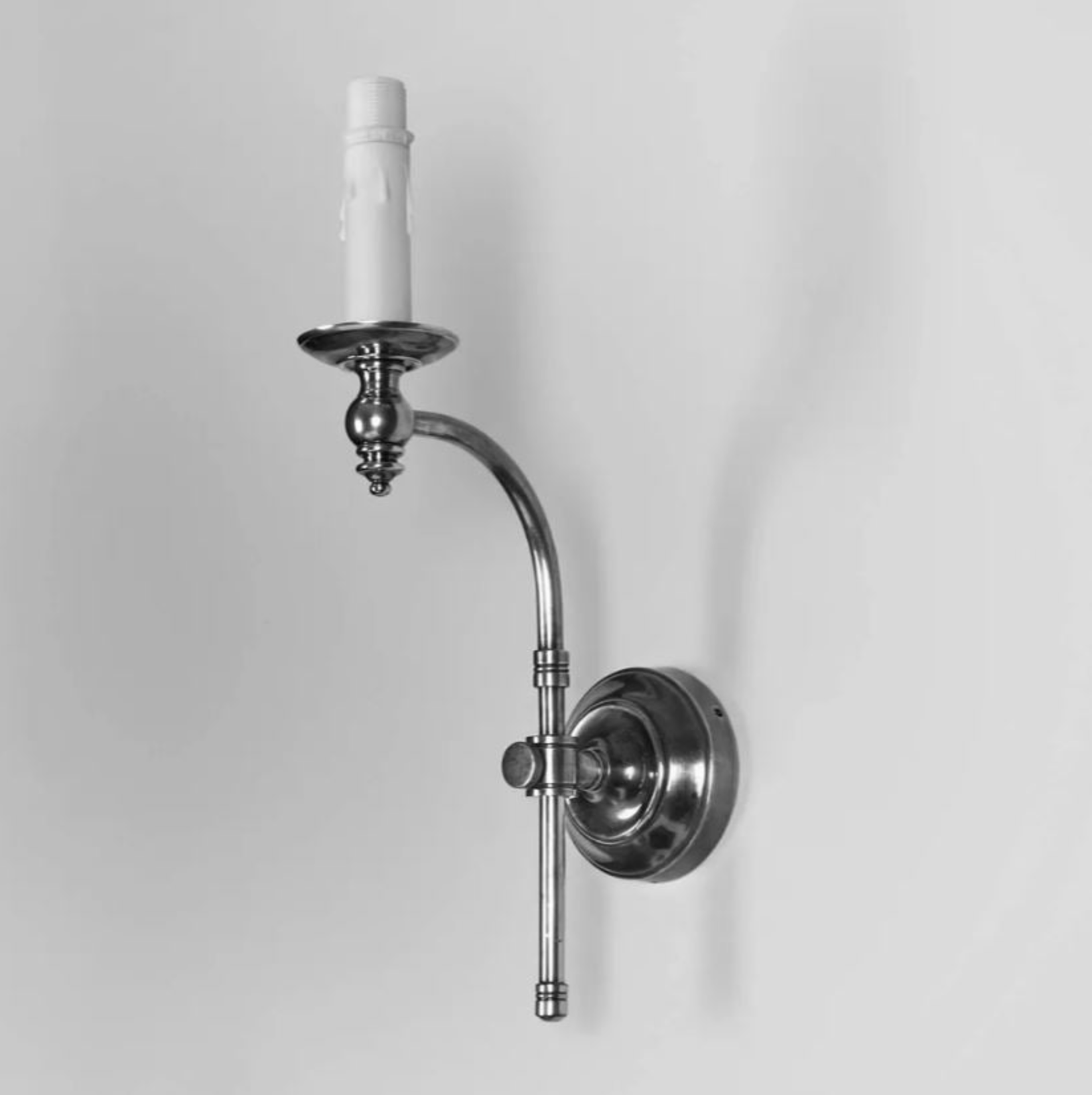 Wall-mounted candle holder with a white candle on a gray background