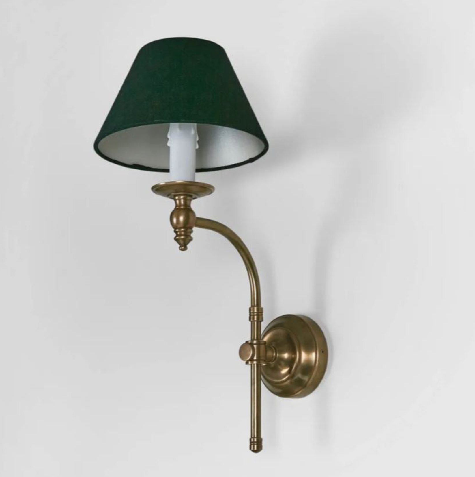 Wall-mounted lamp with green shade and brass arm on a white background