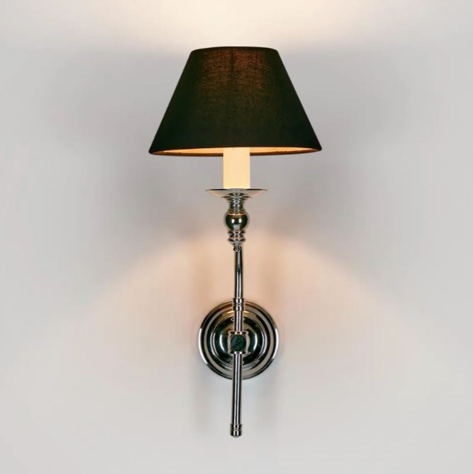 Wall-mounted lamp with black shade and chrome fixture on a light gray background