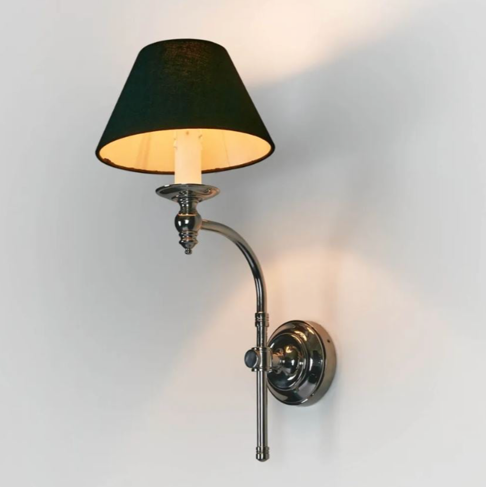 Wall-mounted lamp with black shade and chrome arm on a light gray background