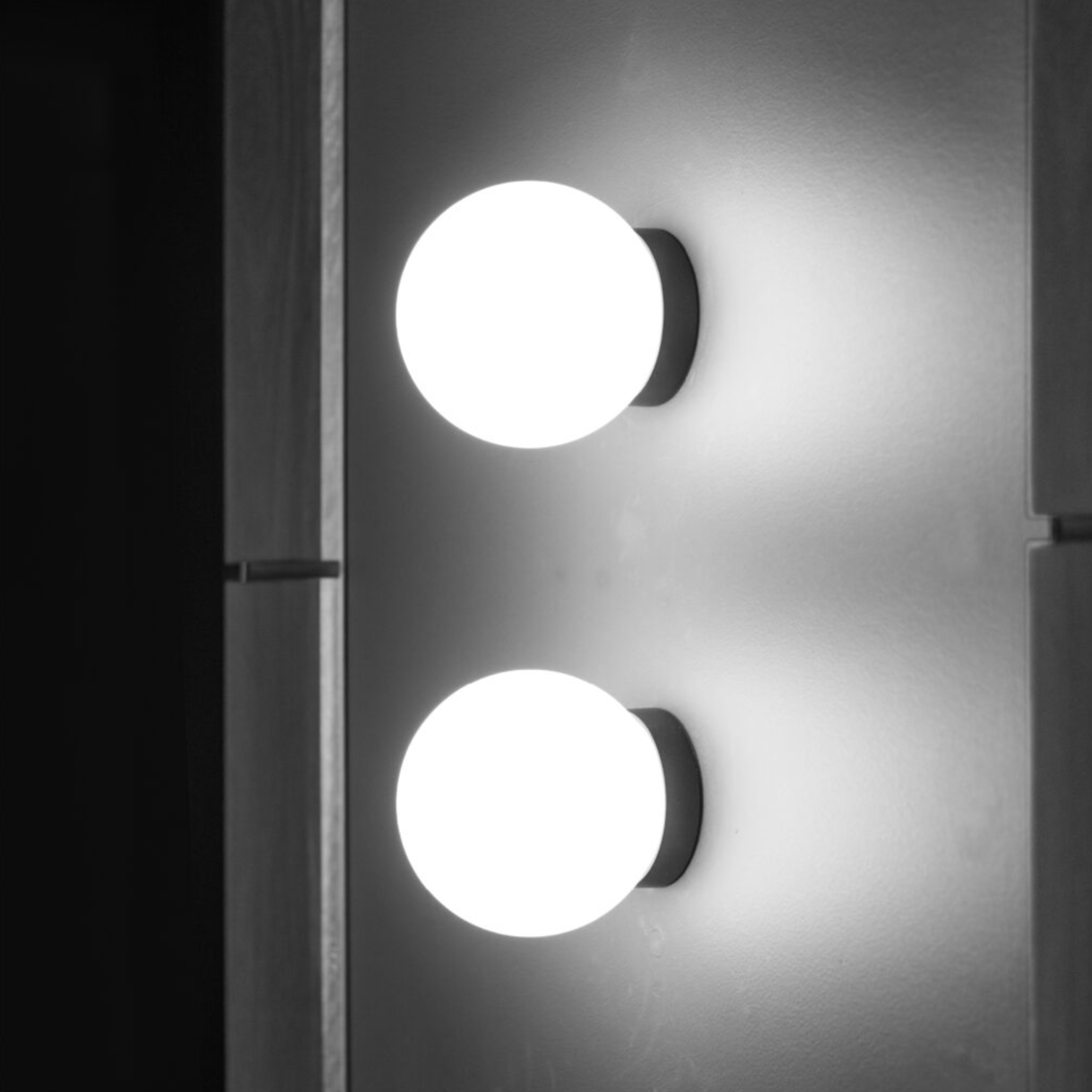 Two round wall lights on a gray wall with a dark frame.