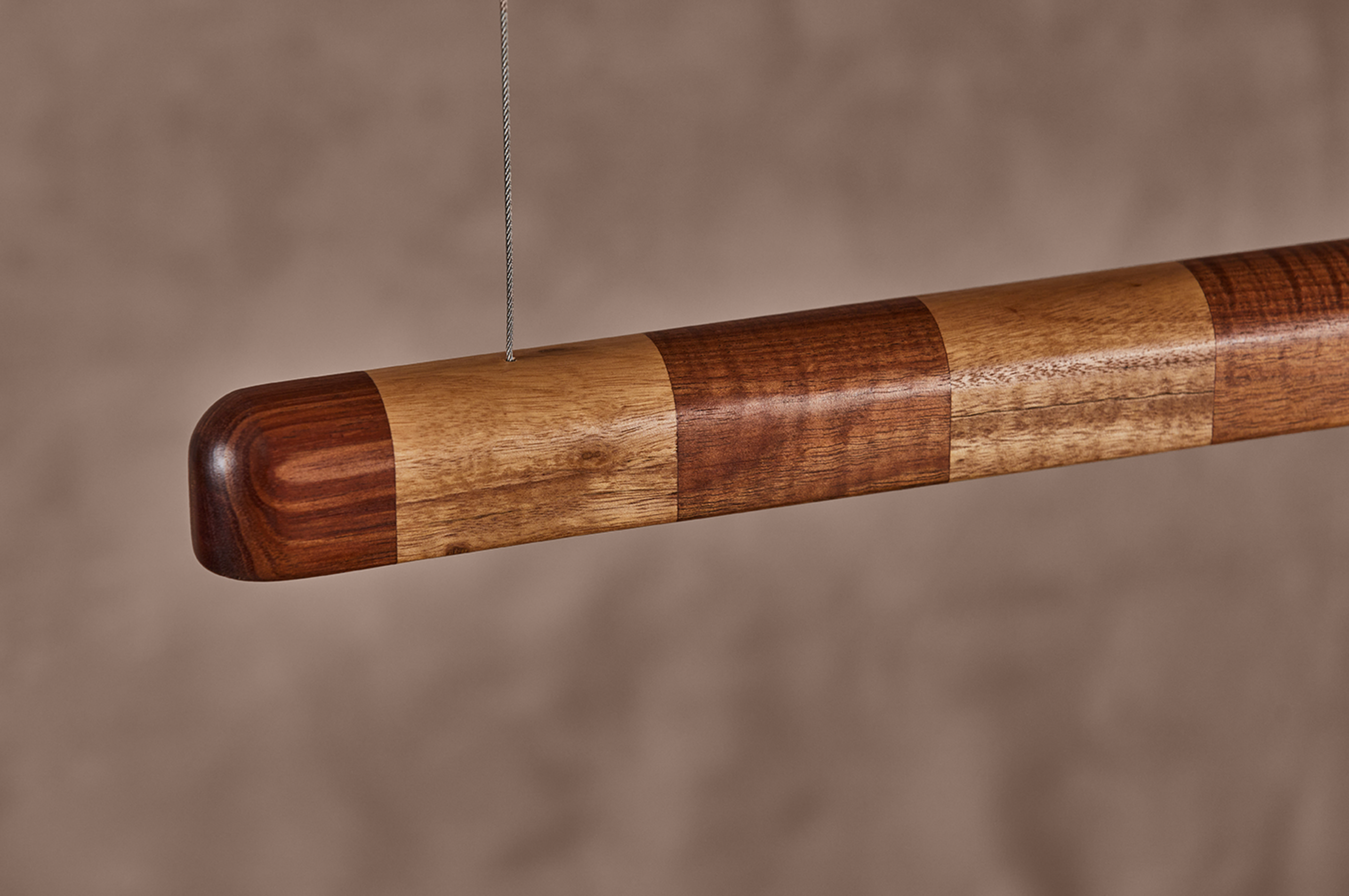 Close-up of Kich pendant light rounded end cap with contrasting Vic Ash and Blackwood timber stripe detail