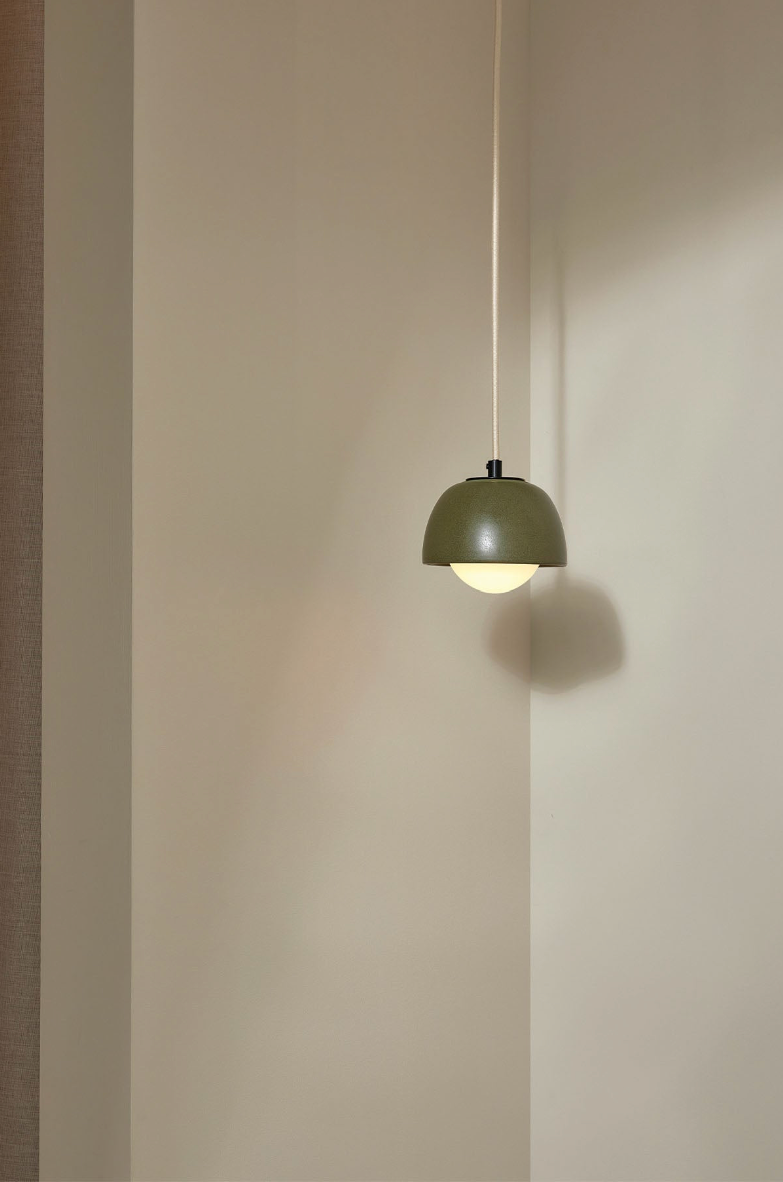 Green pendant light hanging against a plain wall