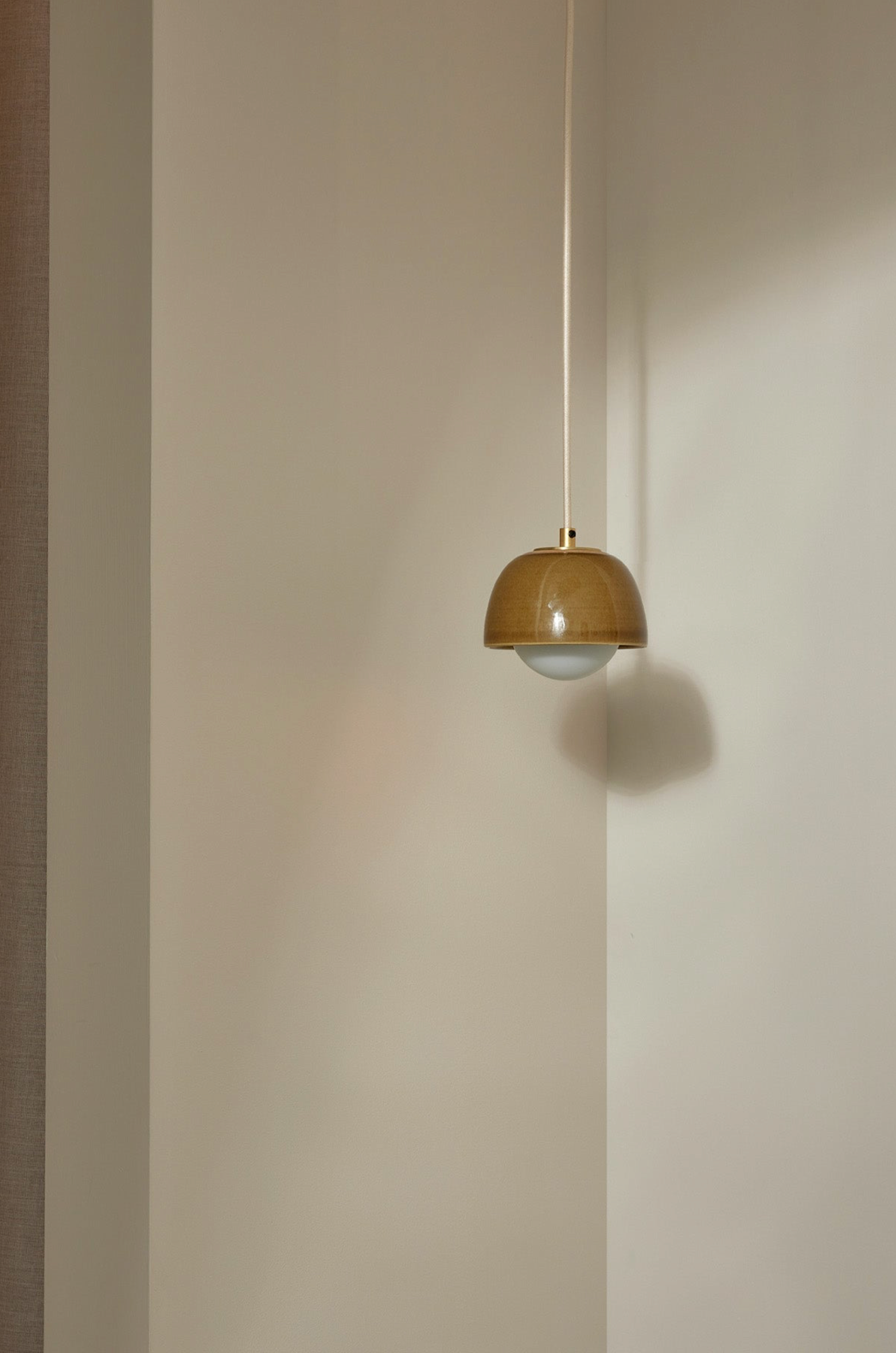 Pendant light fixture hanging against a plain wall