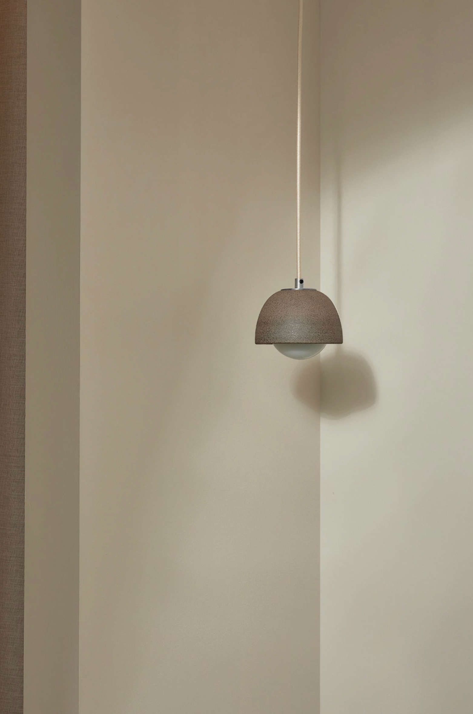 Minimalist pendant light hanging against a plain wall