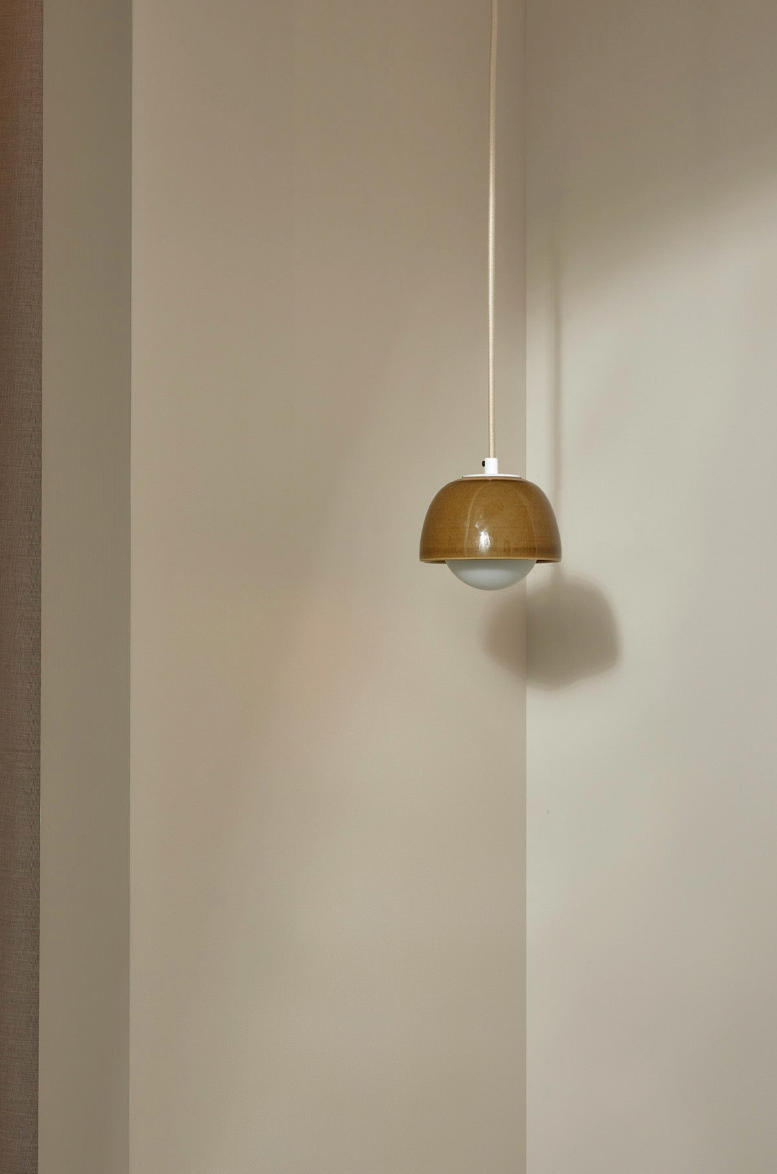 Pendant light fixture hanging against a plain wall