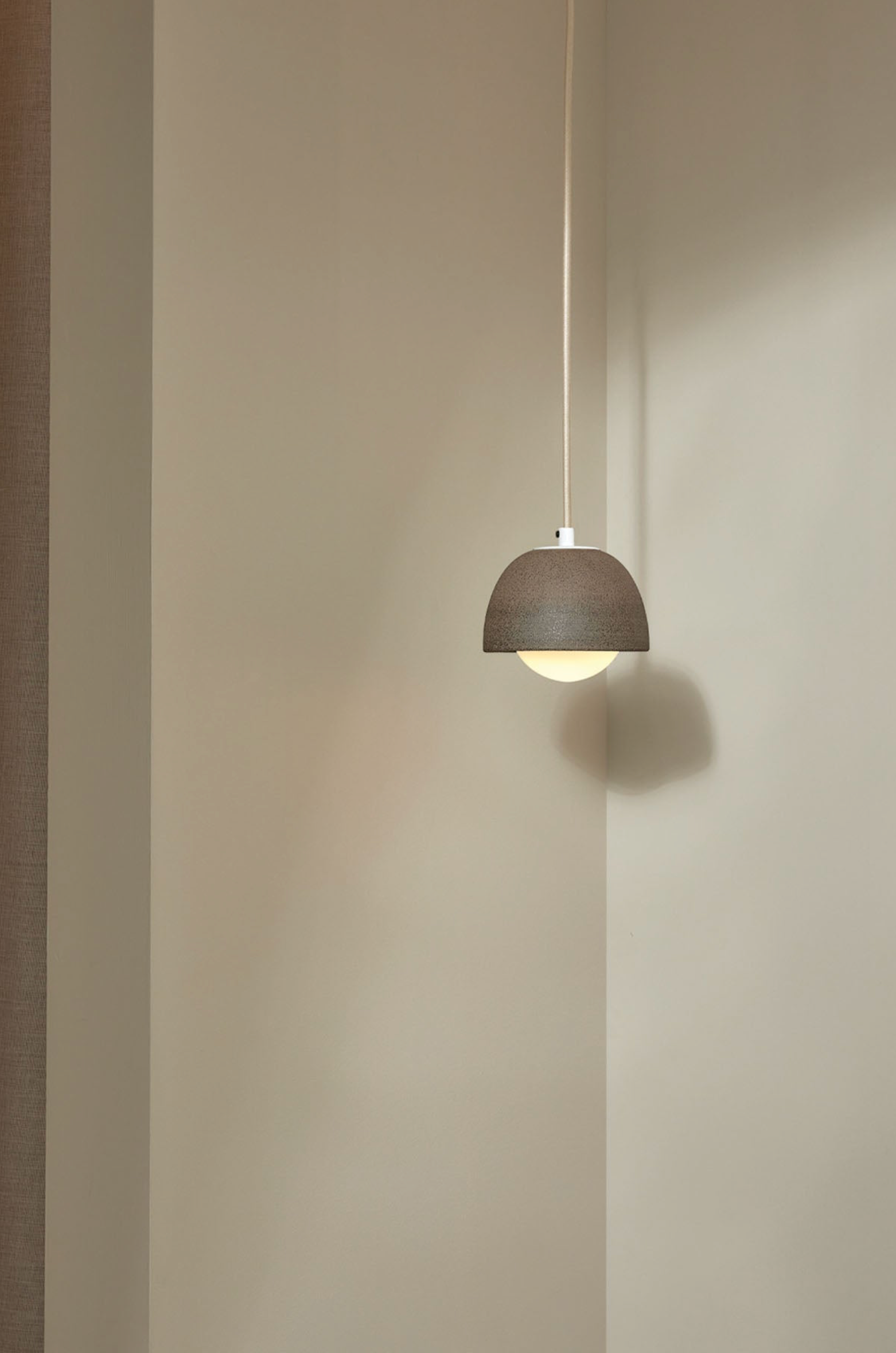 Minimalist pendant light hanging against a plain wall