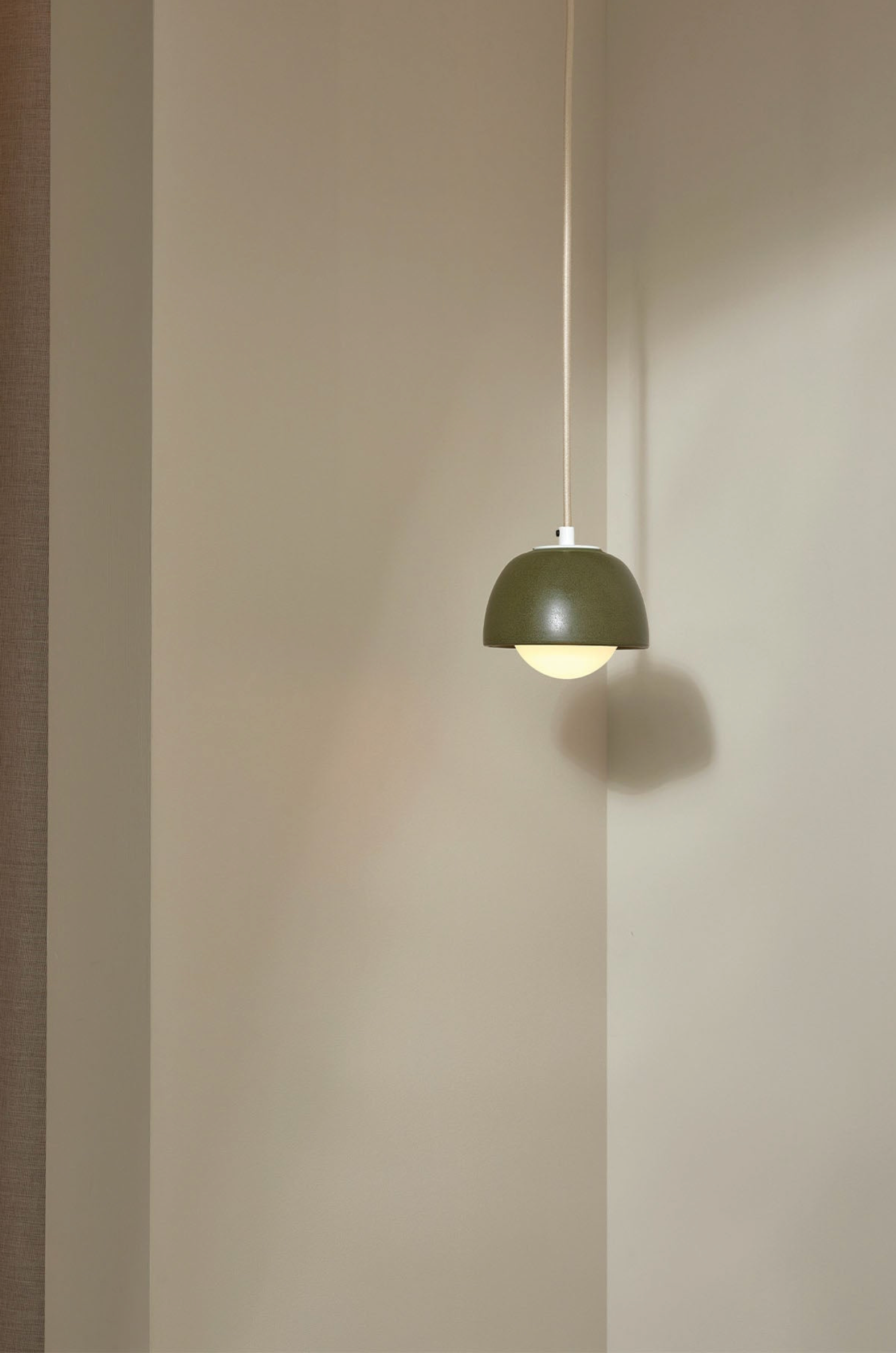 Green pendant light hanging against a plain wall