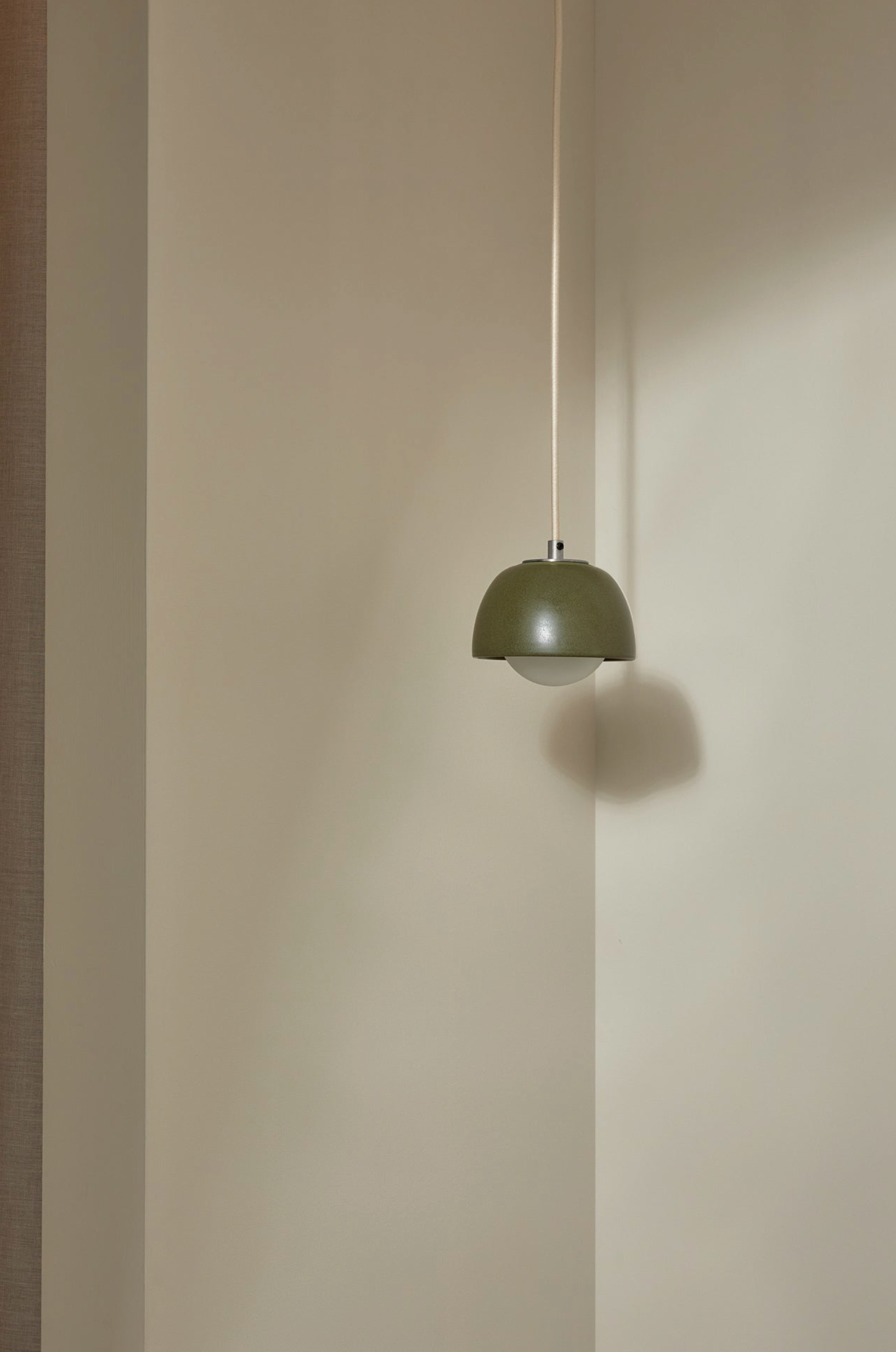 Green pendant light hanging against a plain wall