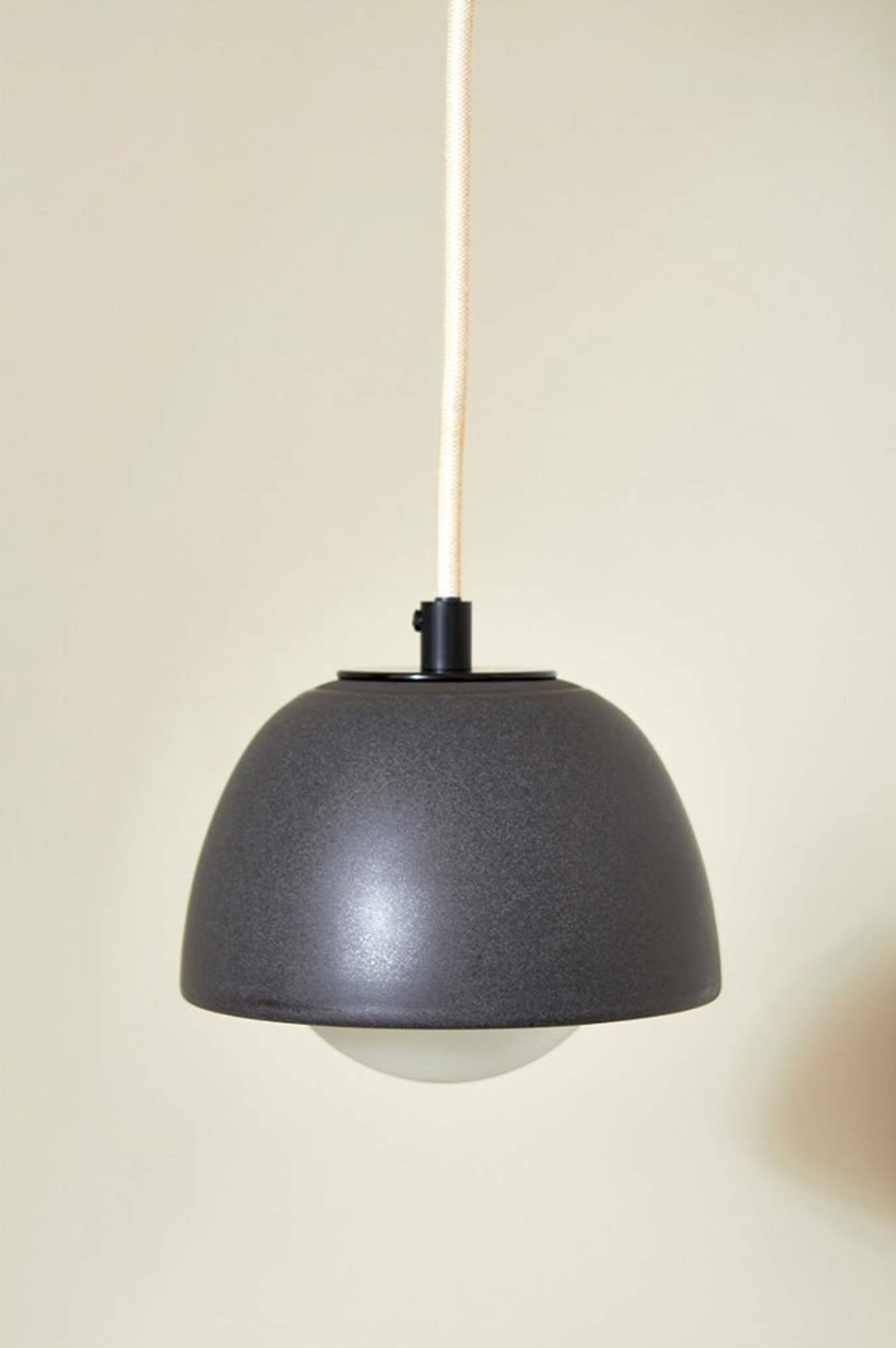 Black pendant light against a beige wall