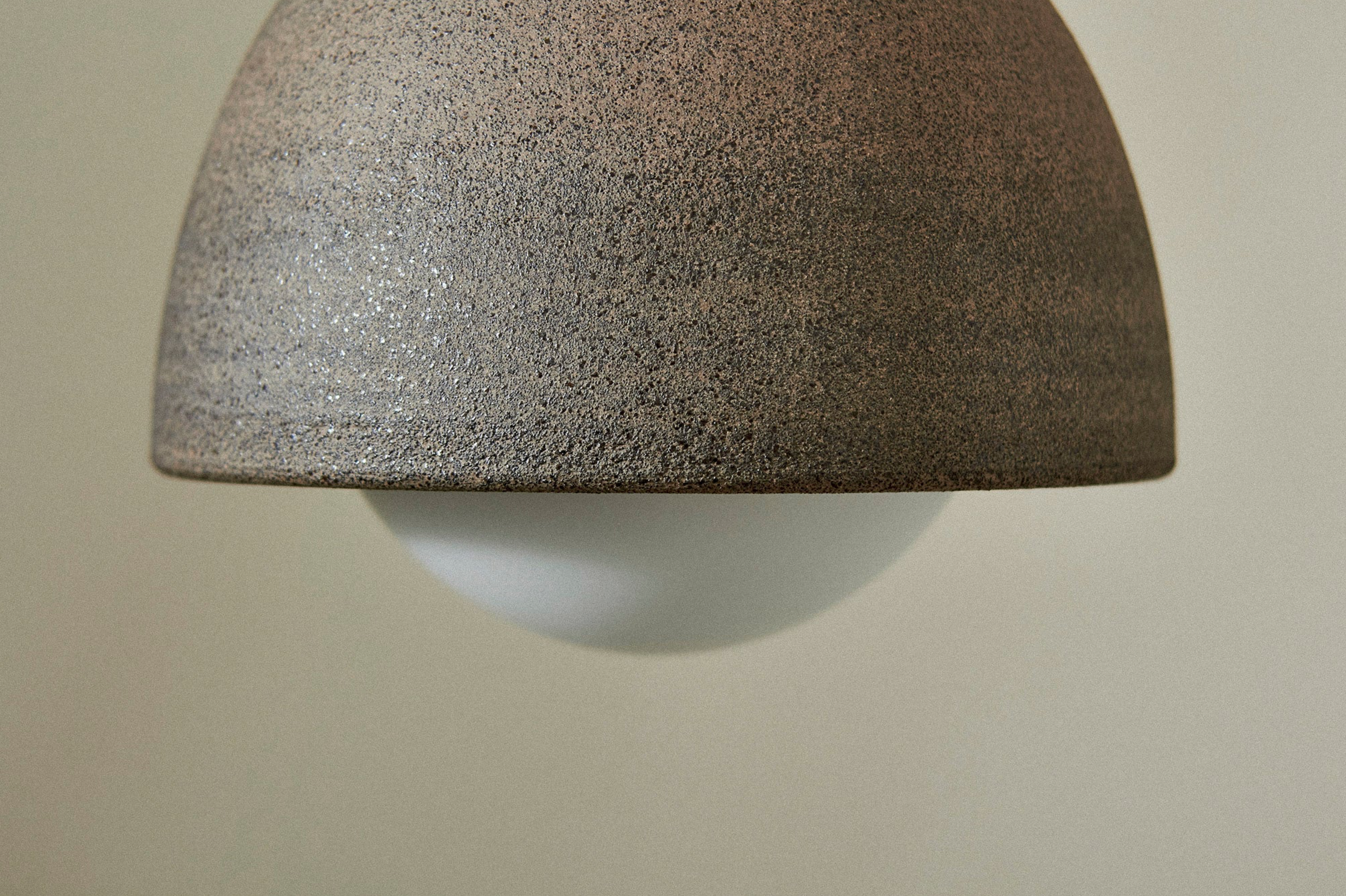 Close-up of a textured ceramic pendant light against a plain background
