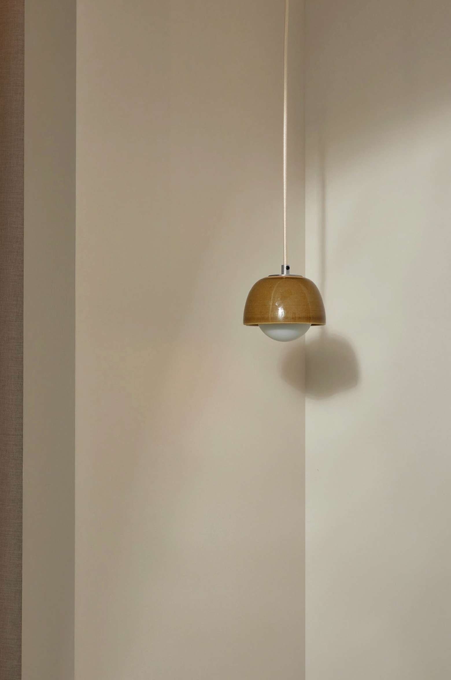 Pendant light fixture hanging against a plain wall