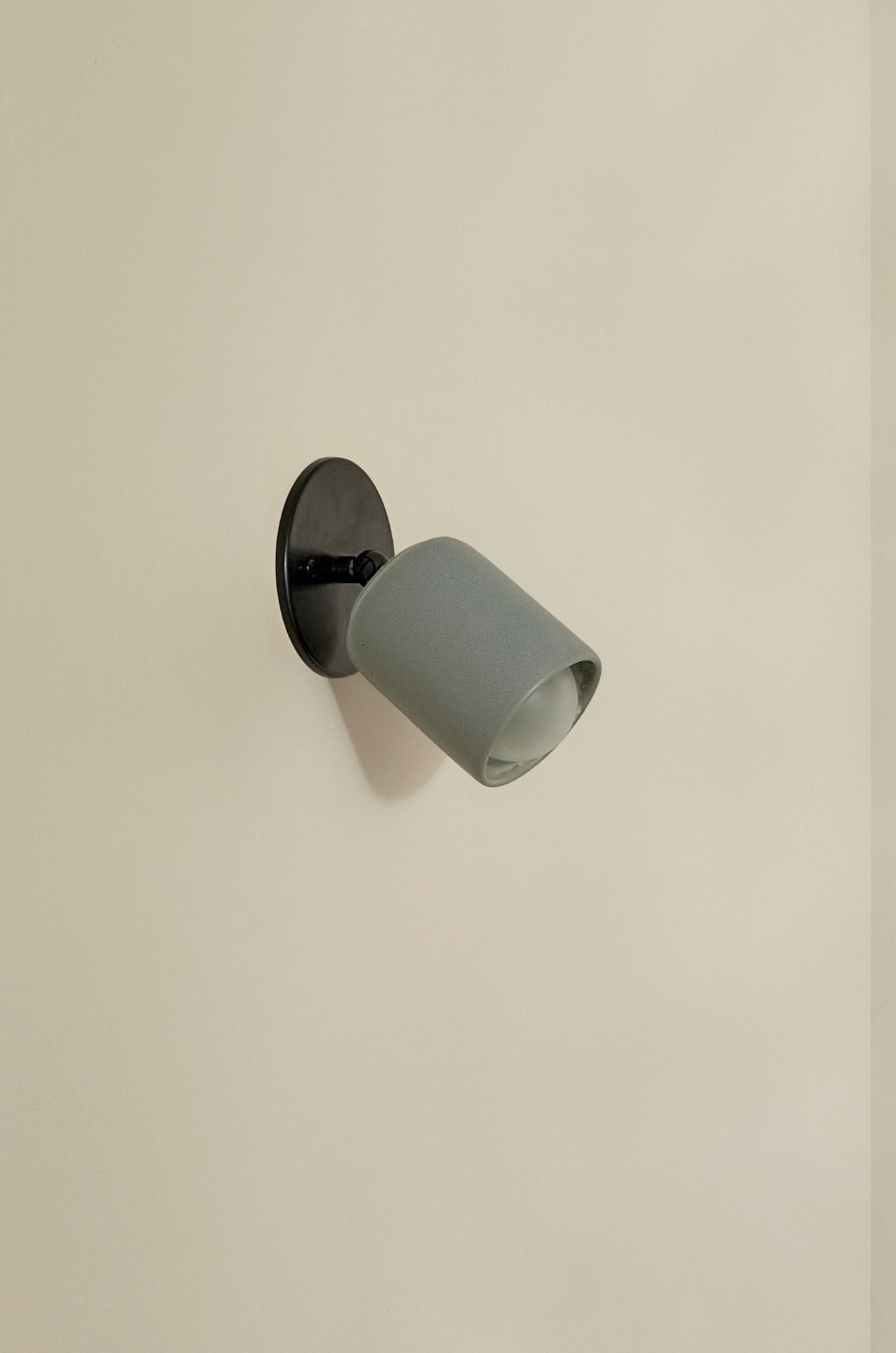 Wall-mounted light fixture with a grey shade on a beige wall