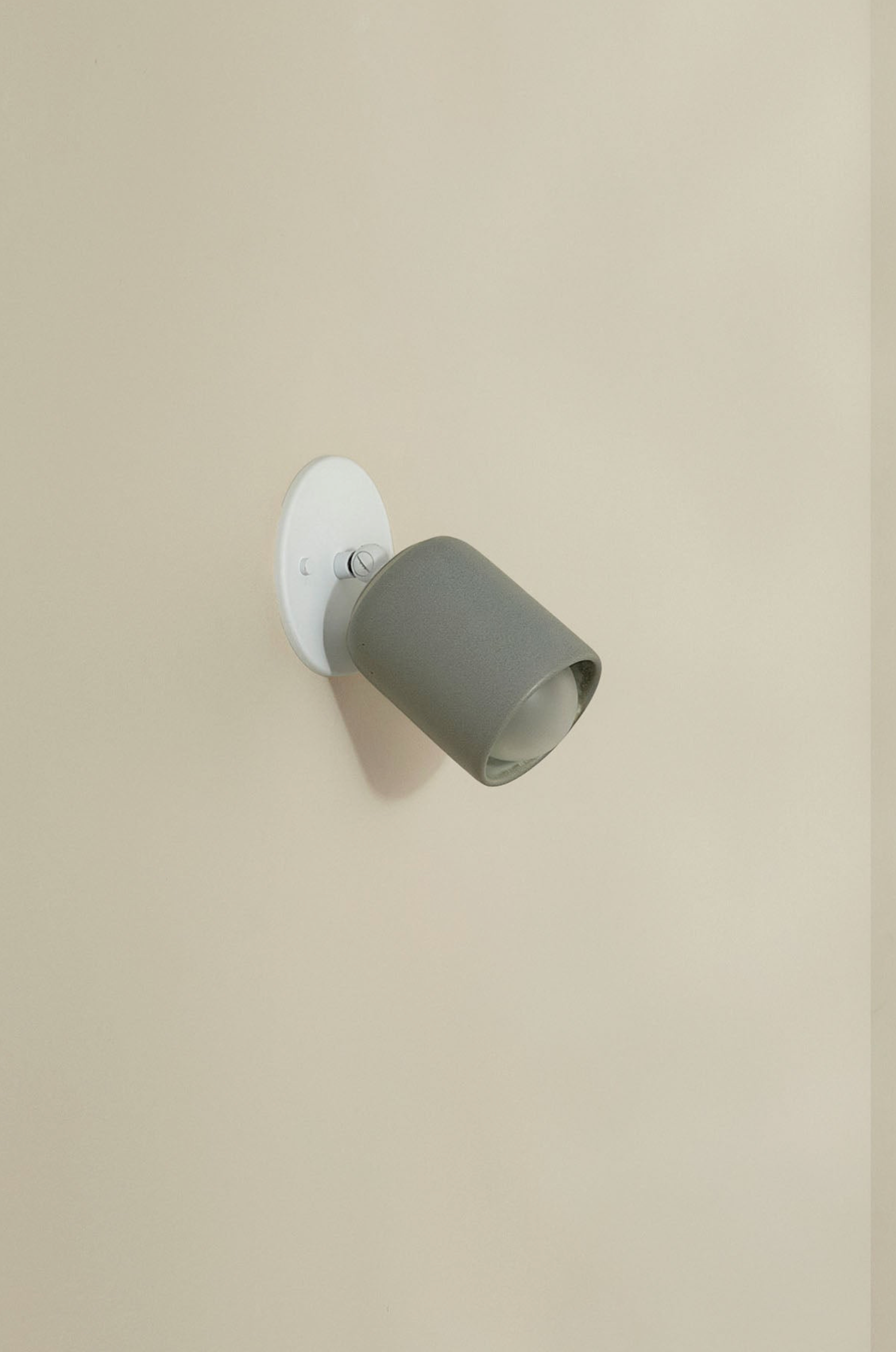 Wall-mounted light fixture with a grey shade on a beige wall
