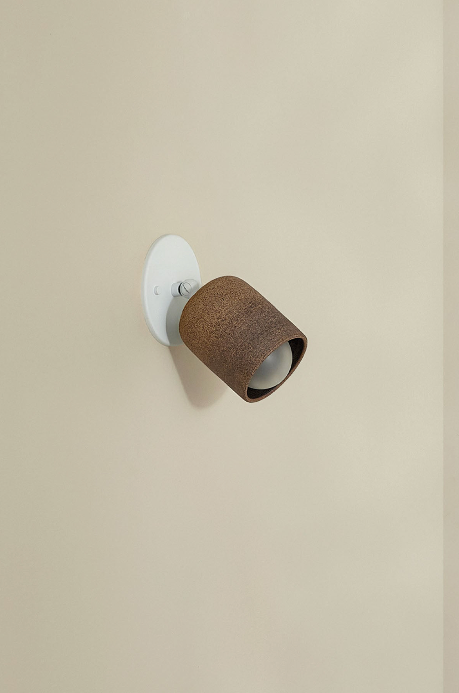 Wall-mounted light fixture with brown shade on a beige wall