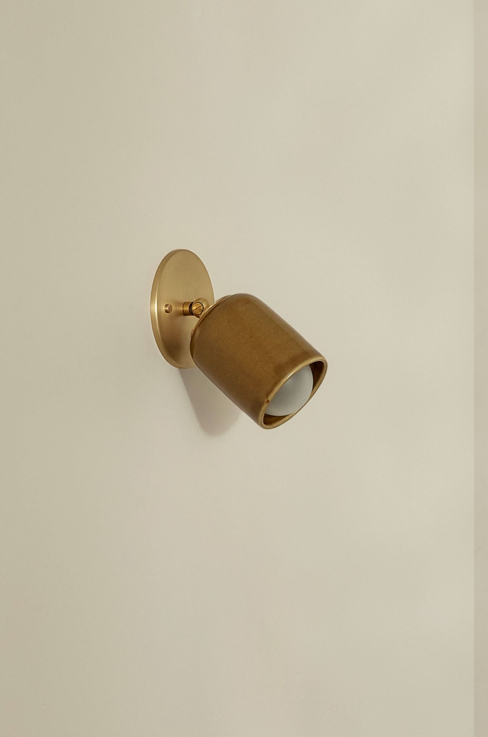 Bronze wall-mounted light fixture on a beige wall