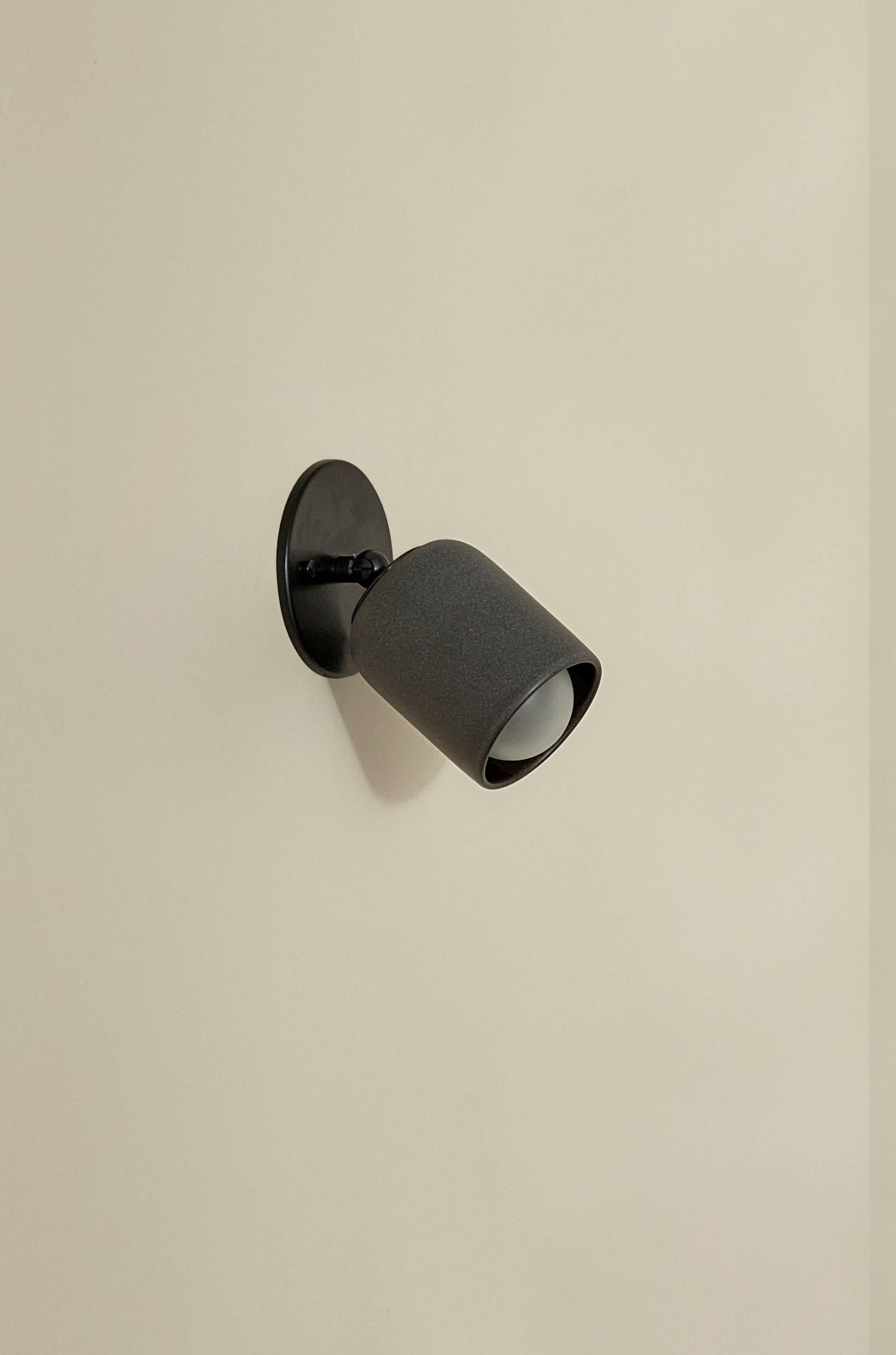 Black wall-mounted indoor ceramic light fixture on a beige wall