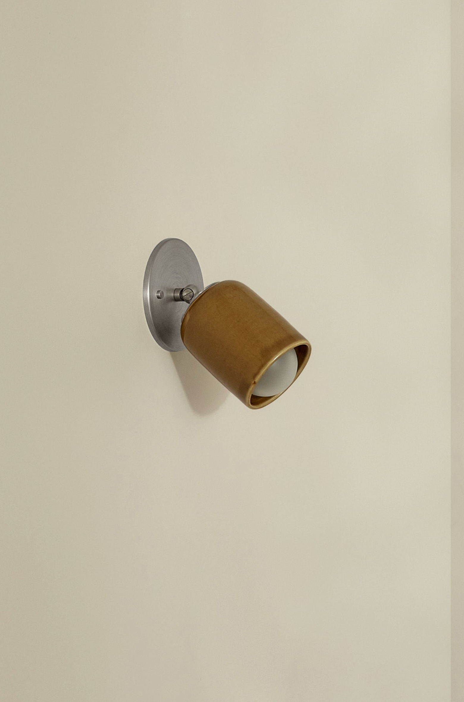 Wall-mounted light fixture with brown shade on a beige wall