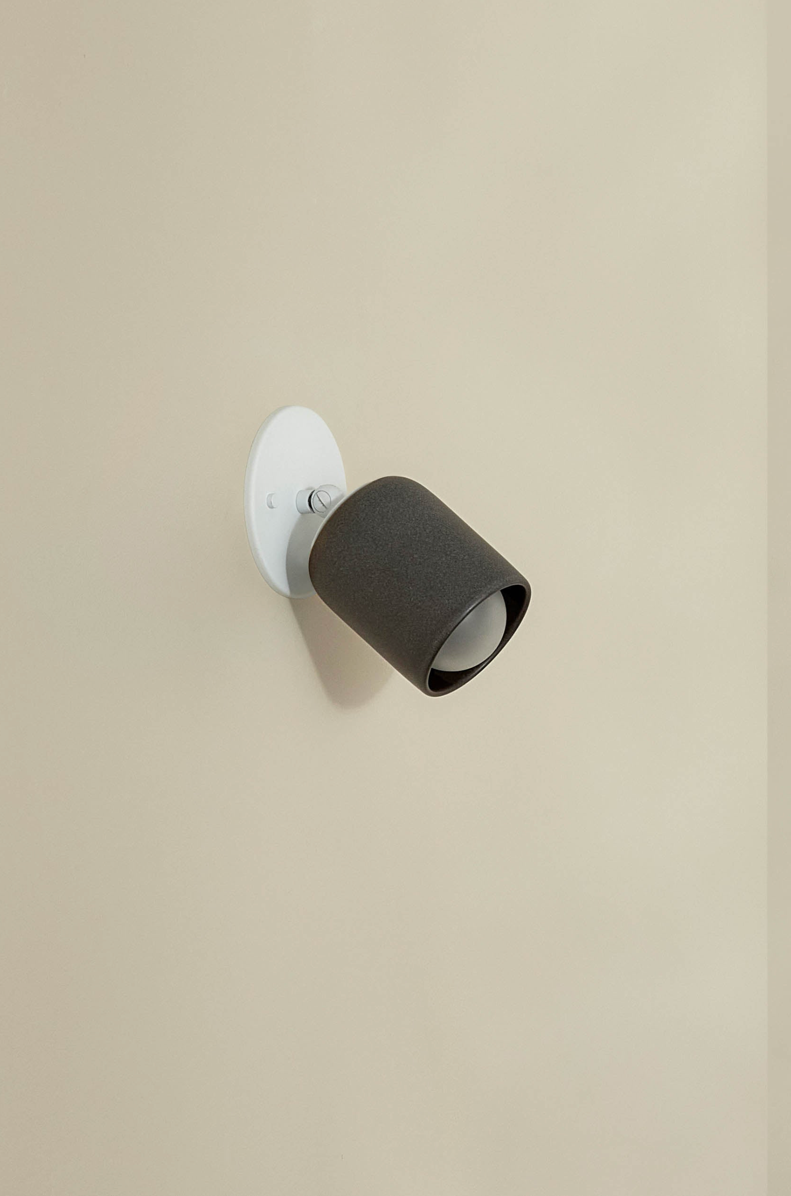 Wall-mounted light fixture with black shade on a beige wall