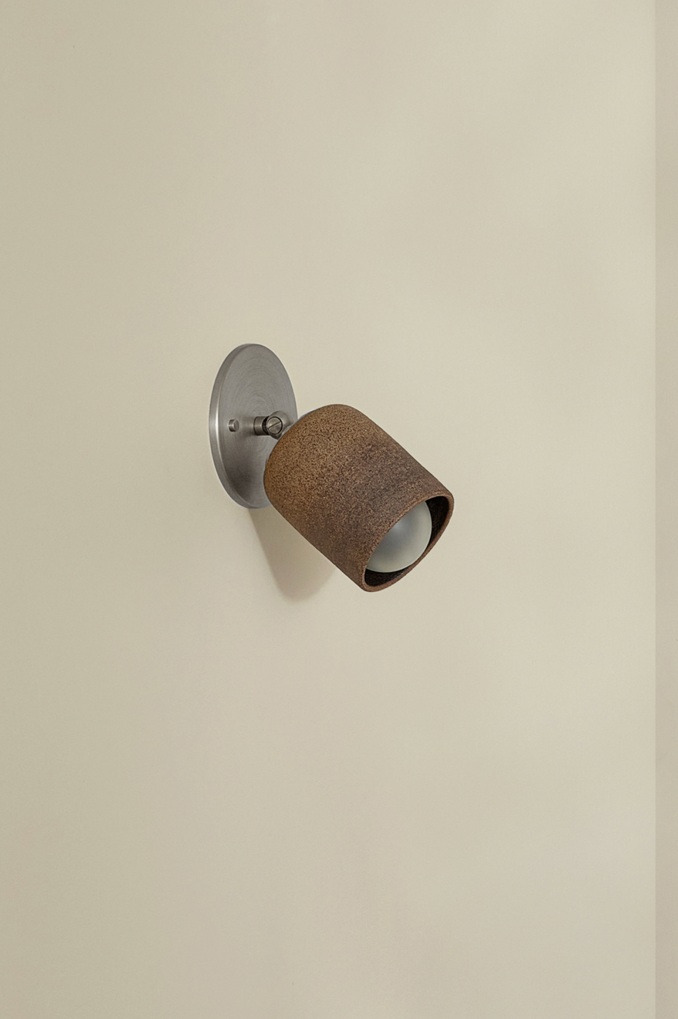 Wall-mounted light fixture with brown shade on a beige wall