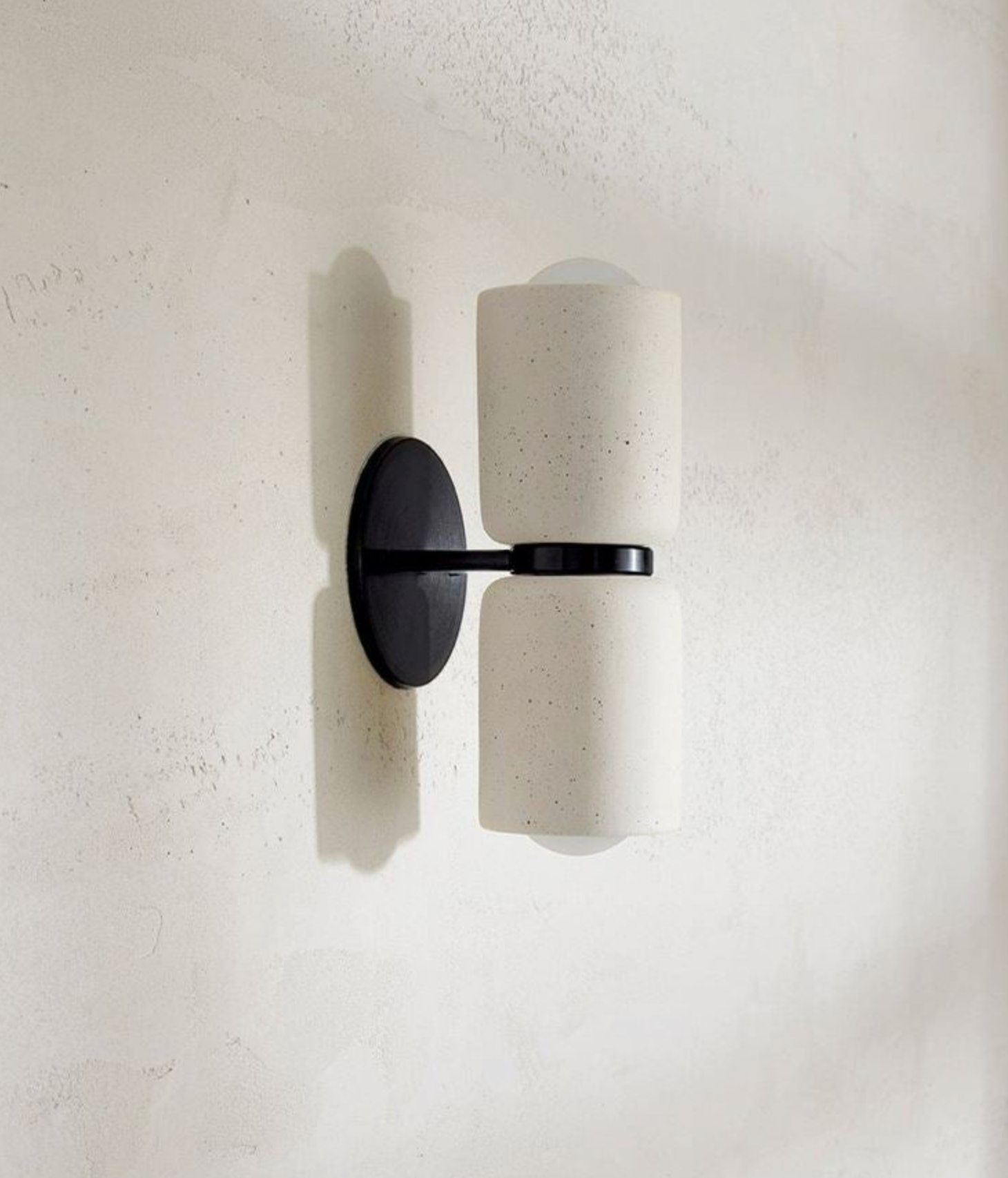 Wall-mounted light fixture with black finish on a textured white wall
