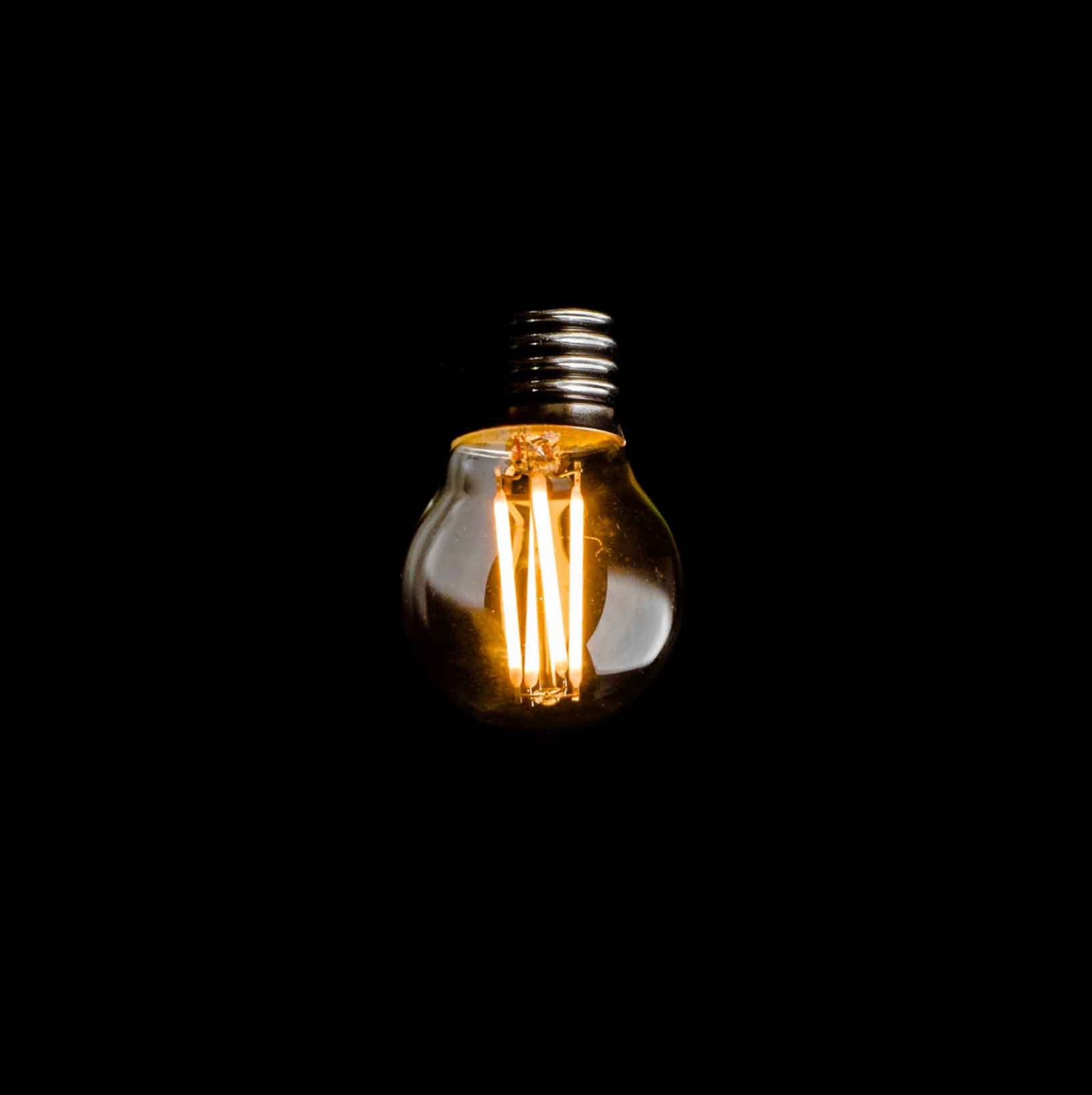 Light bulb filament glowing against a black background