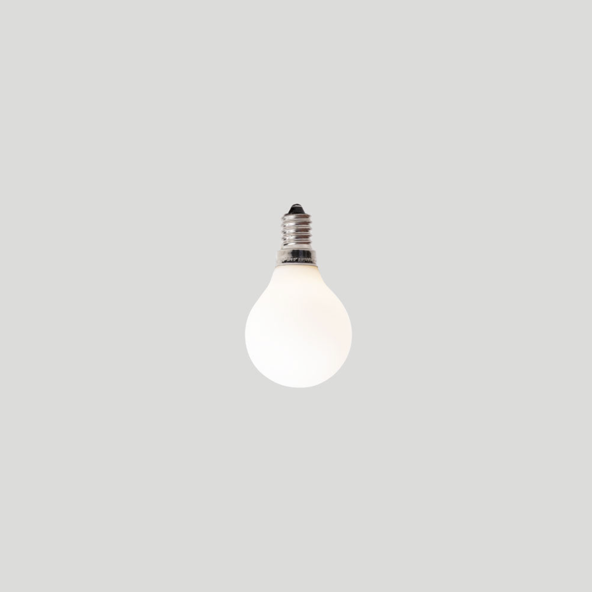White frosted light bulb on a light grey background