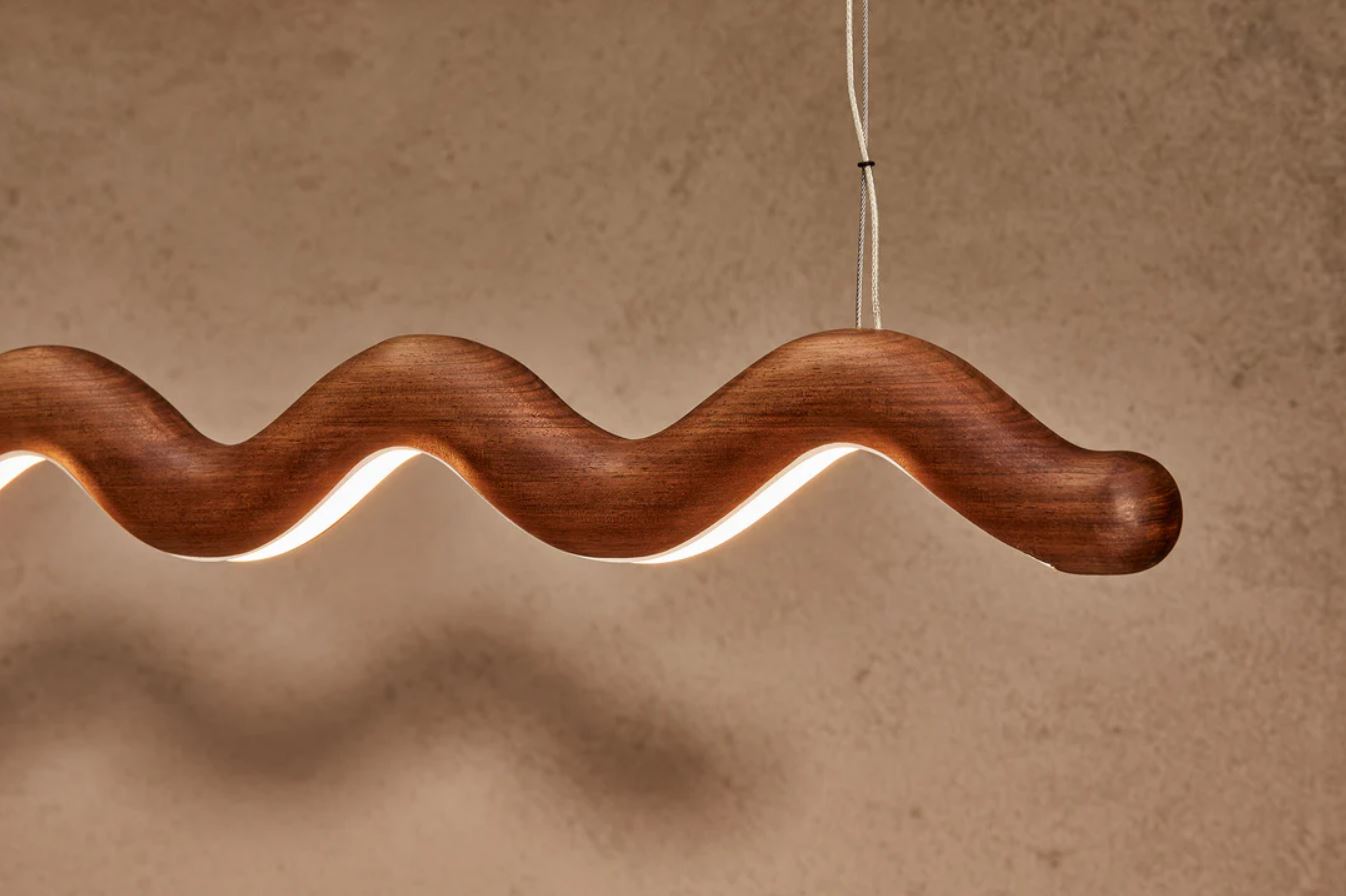 Wavy wooden linear pendant light on a beige background