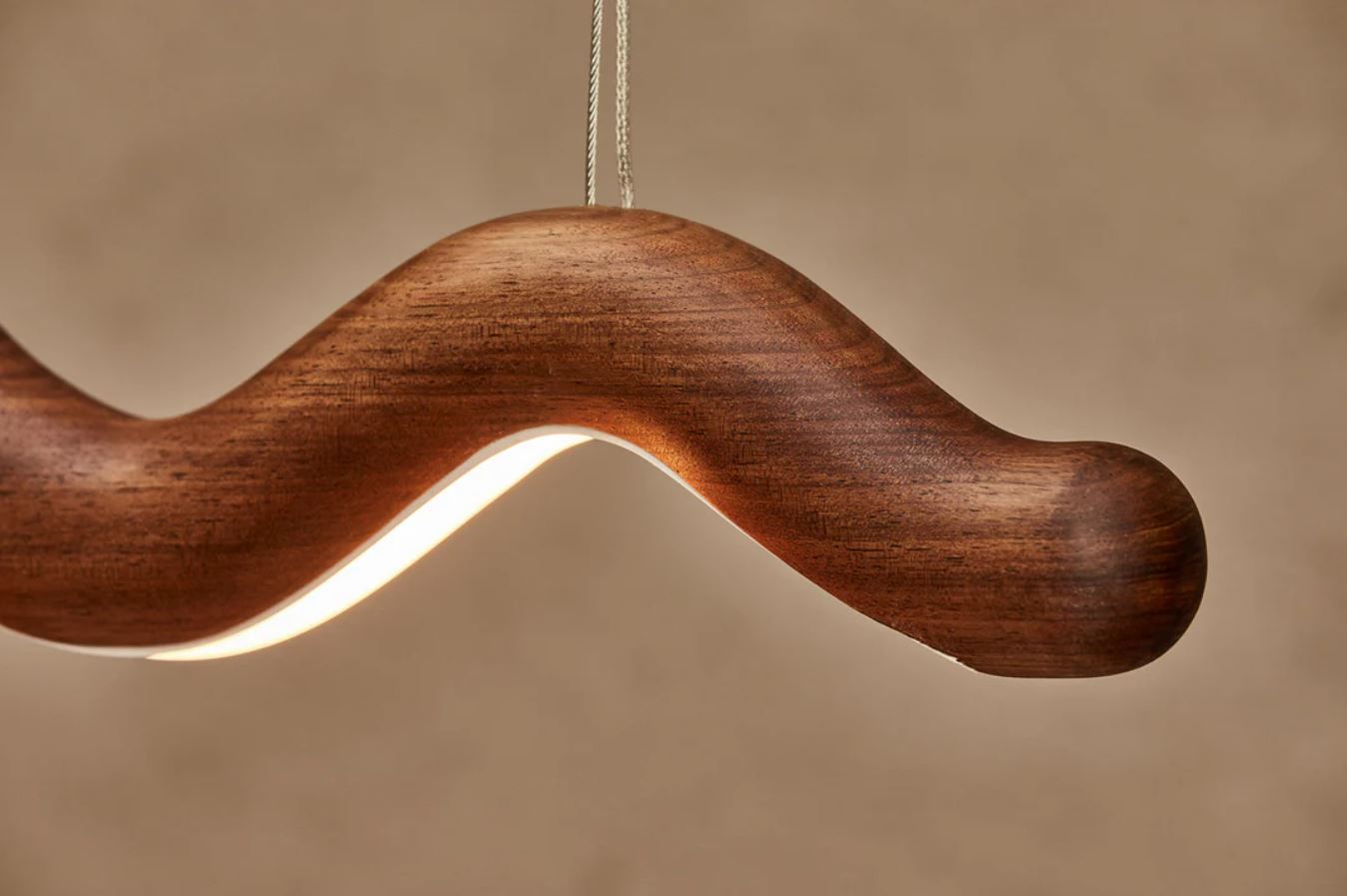 Wooden linear pendant light with wavy design on a beige background