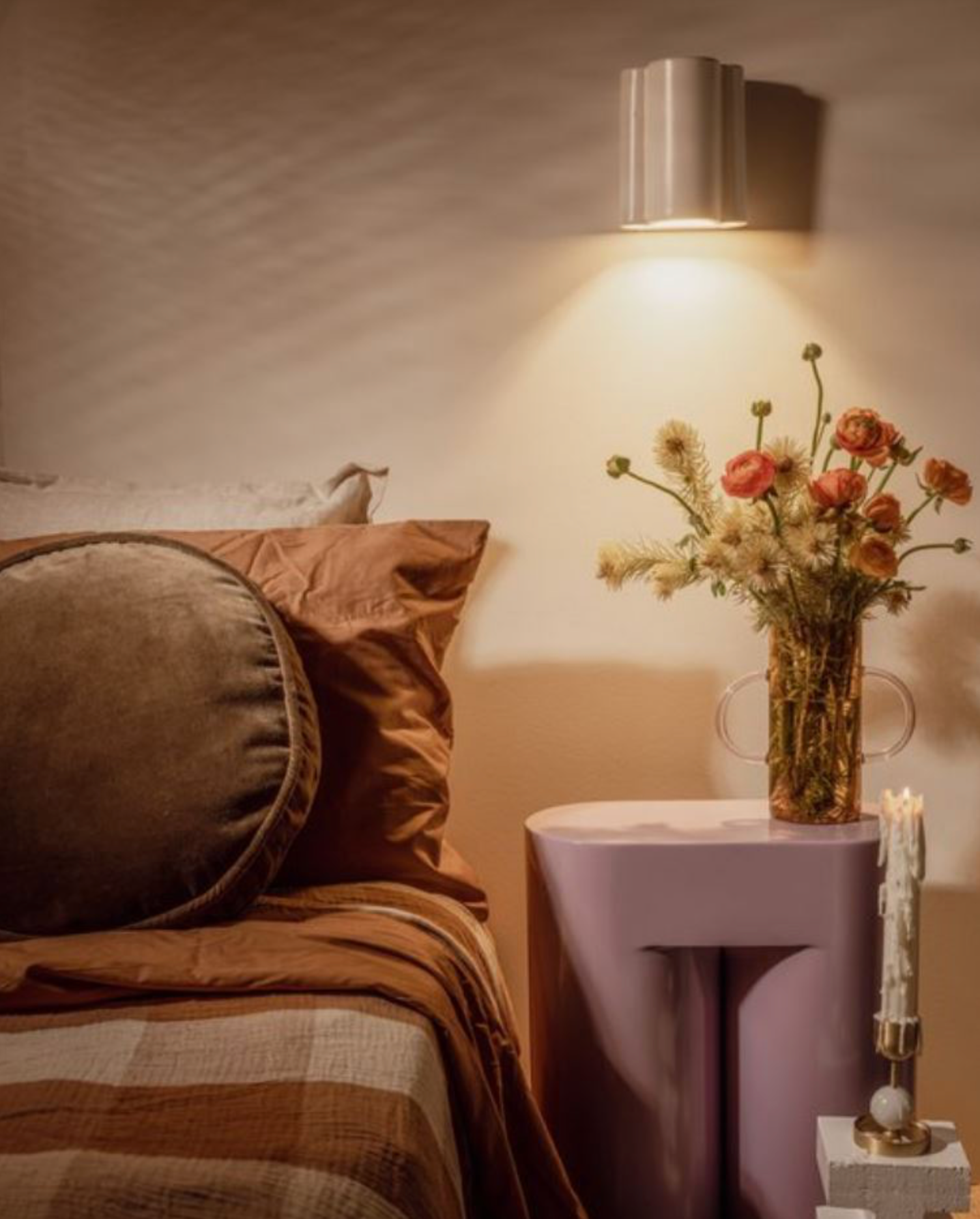 Neatly arranged bedroom with a bed, side table, and decorative elements.