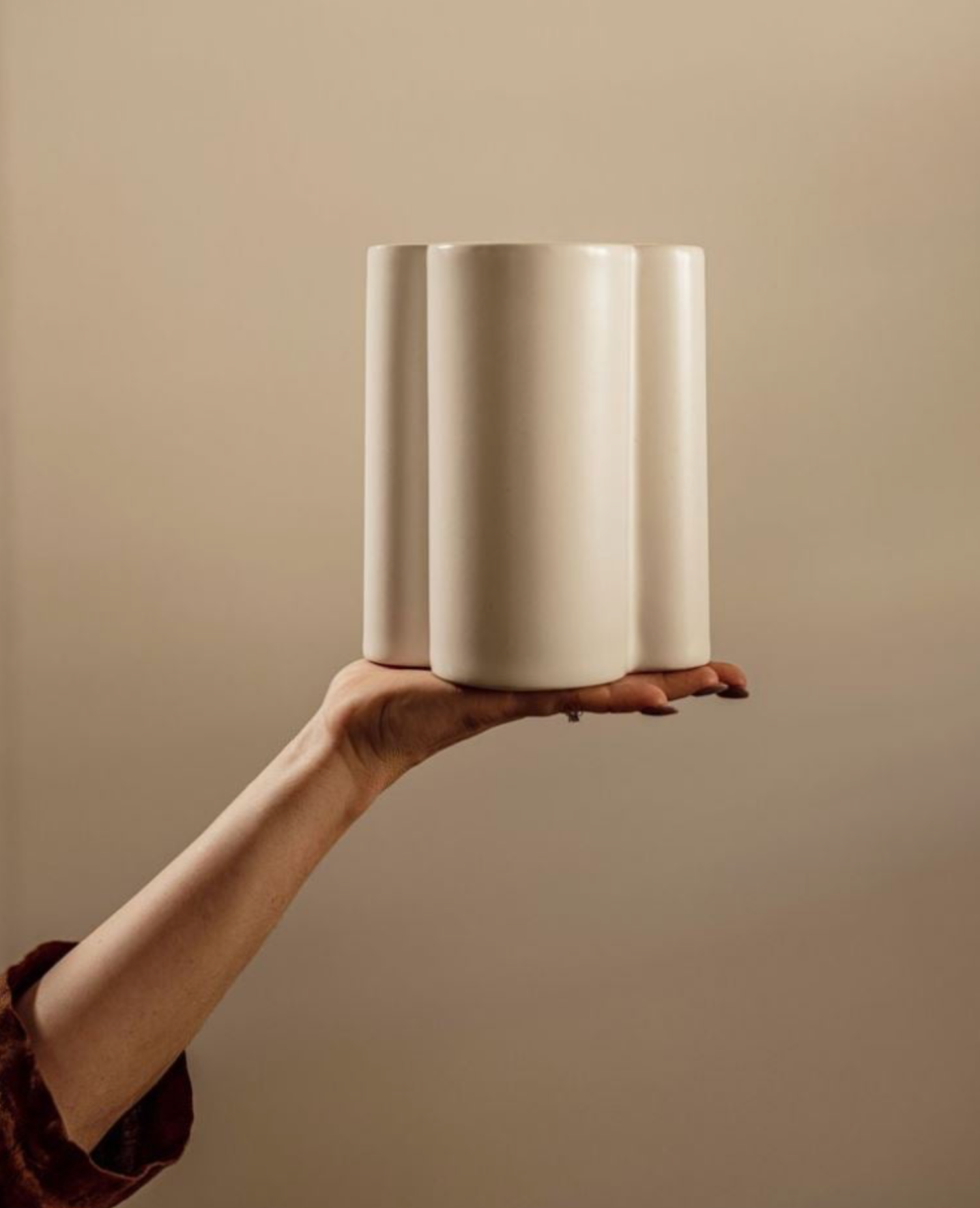 Hand holding a cylindrical ceramic light against a plain background