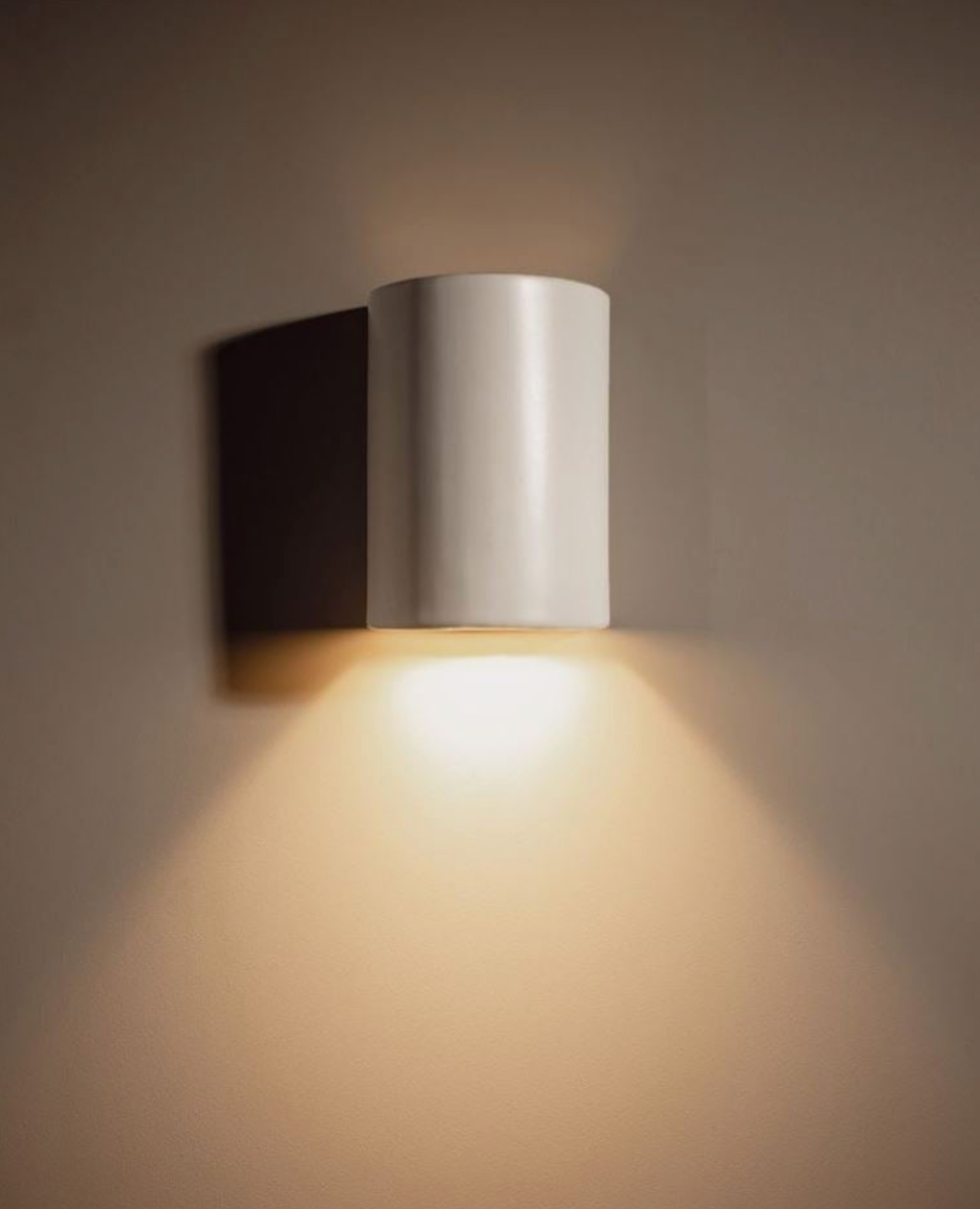 Modern wall-mounted light fixture casting a warm glow on a neutral background