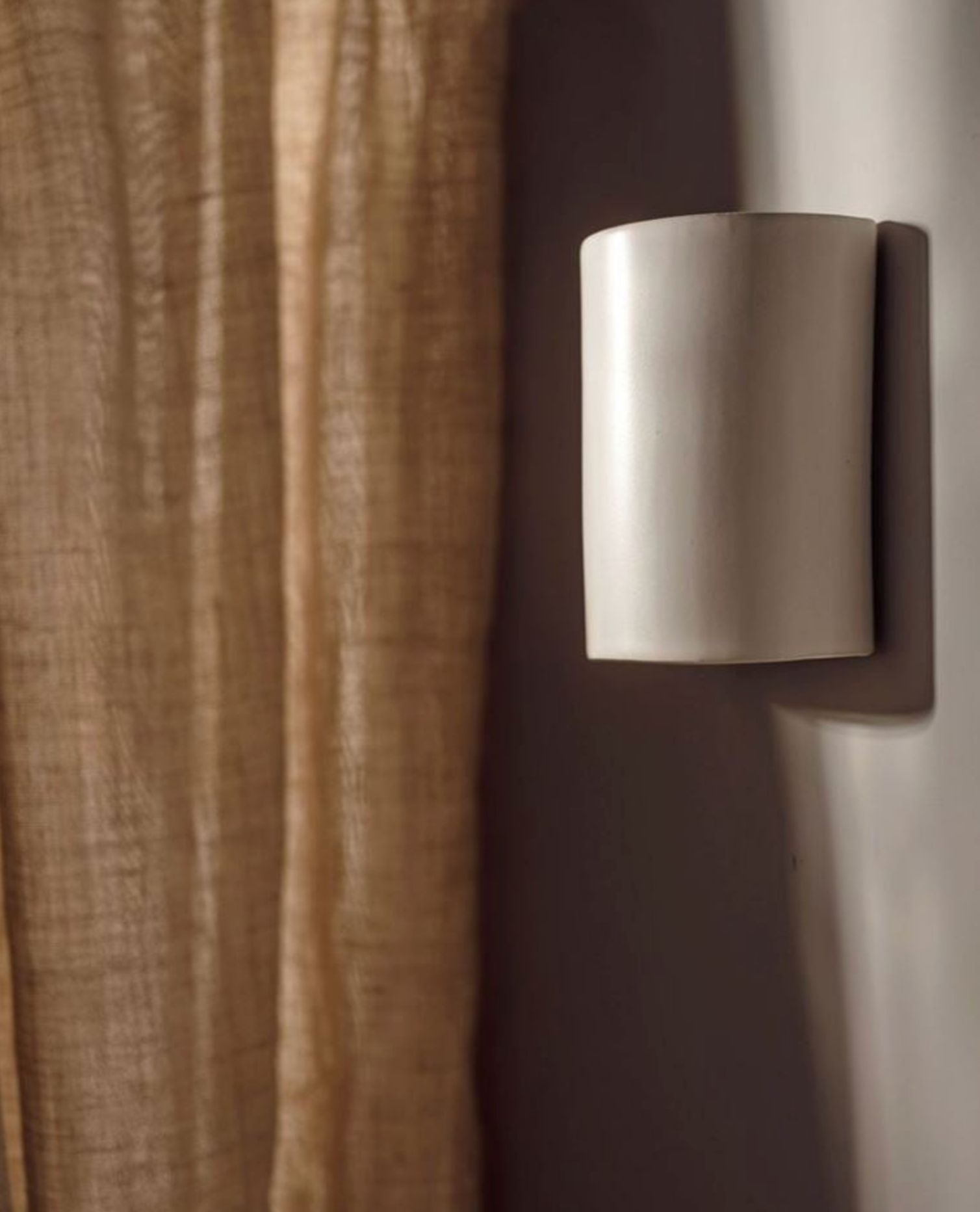 Cylindrical wall-mounted light fixture on a neutral background
