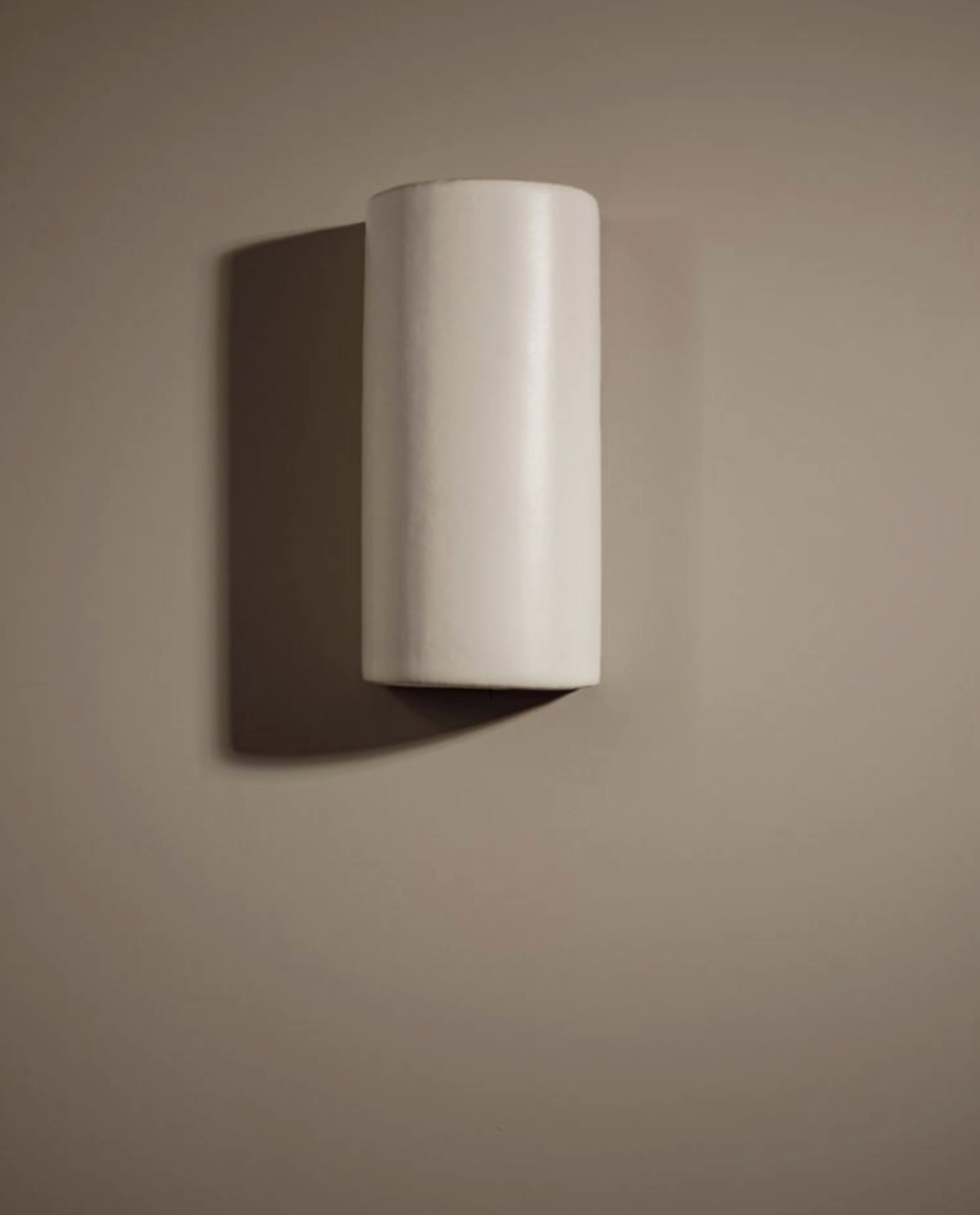 Cylindrical ceramic interior wall light fixture on a beige wall