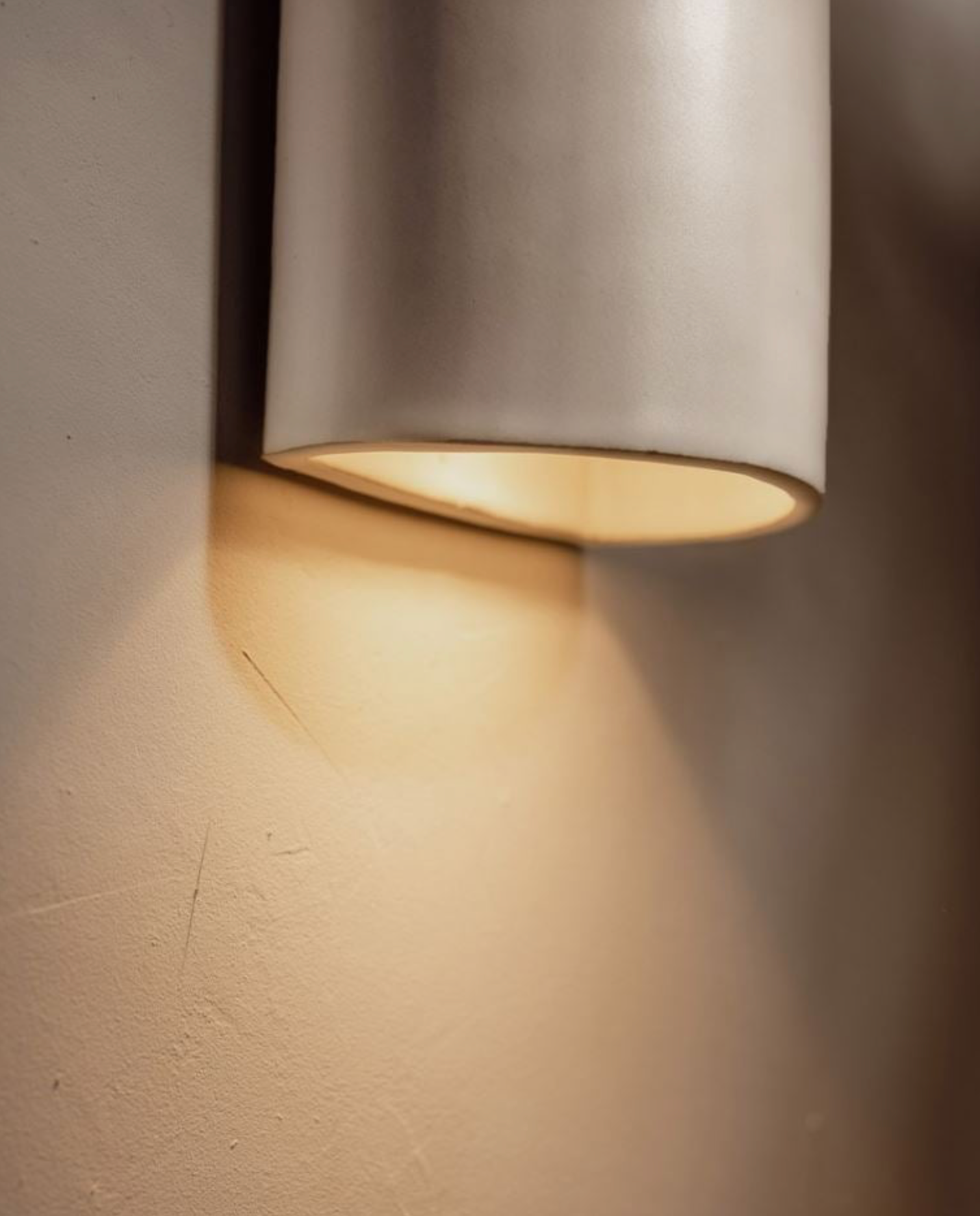 Wall-mounted light fixture casting a warm glow on a textured wall.