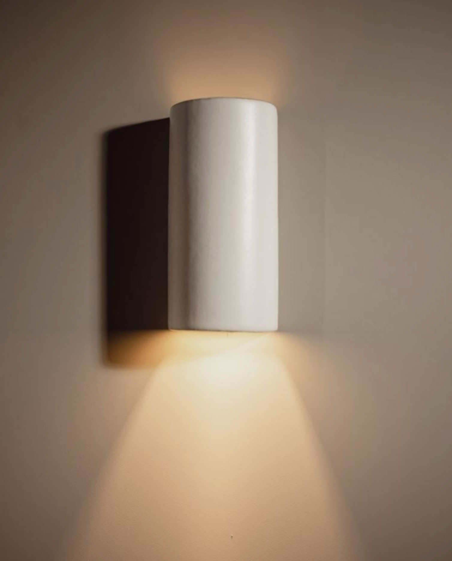 Modern wall-mounted light fixture casting a warm glow on a neutral background