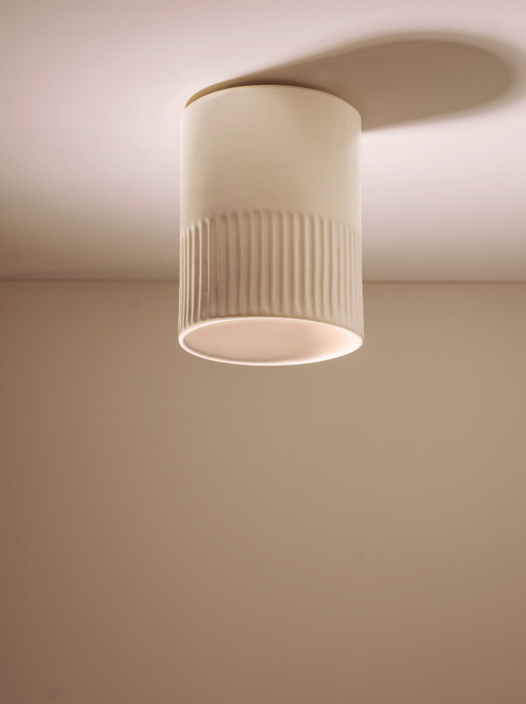 Ribbed ceramic ceiling light fixture on a plain wall