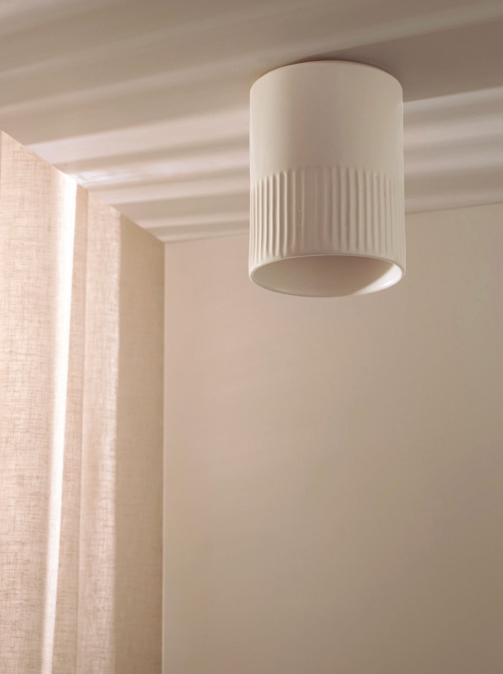 Ceiling light fixture in a neutral-colored room with curtains