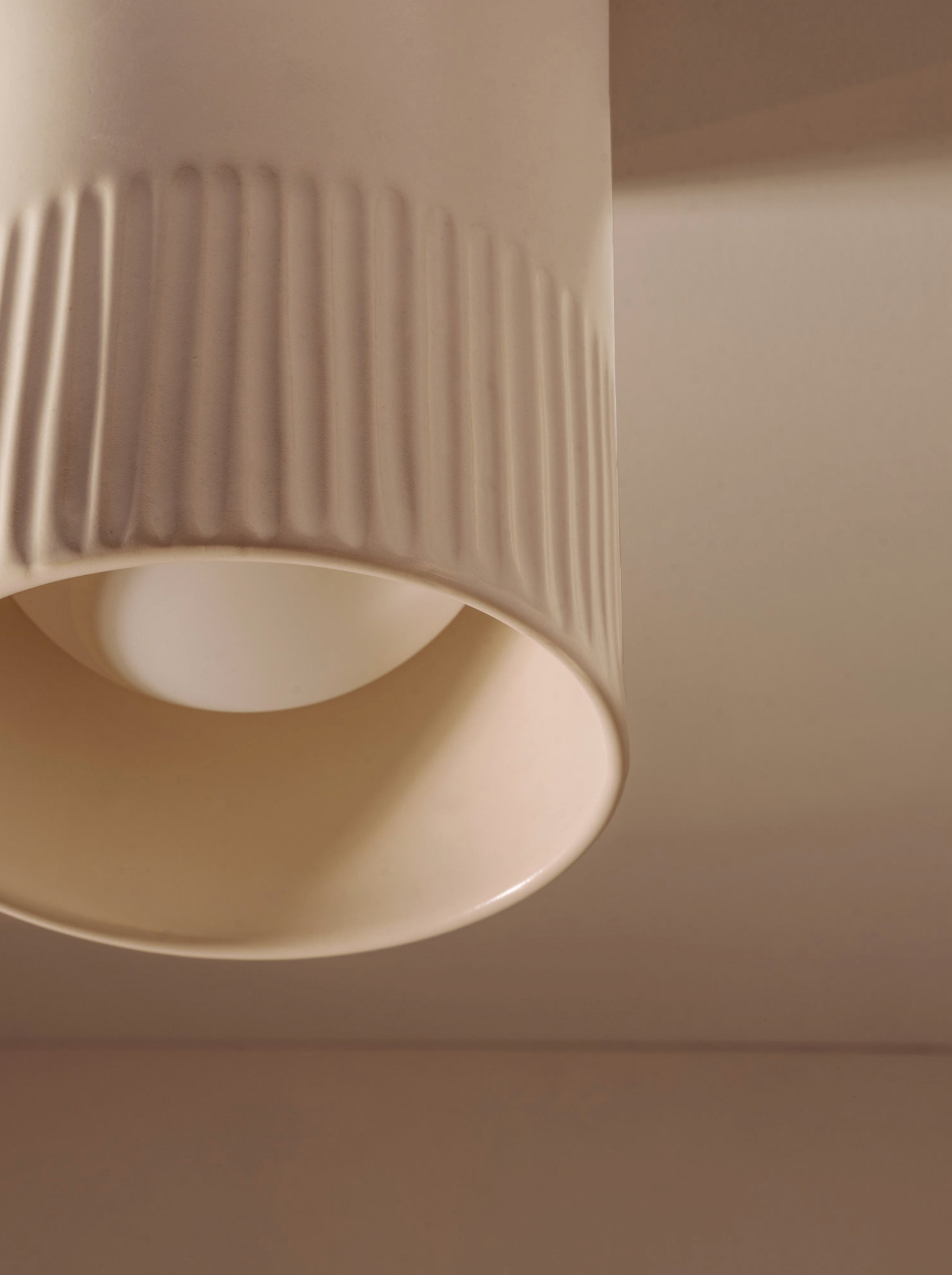 Close-up of a beige cylindrical light fixture on a neutral background