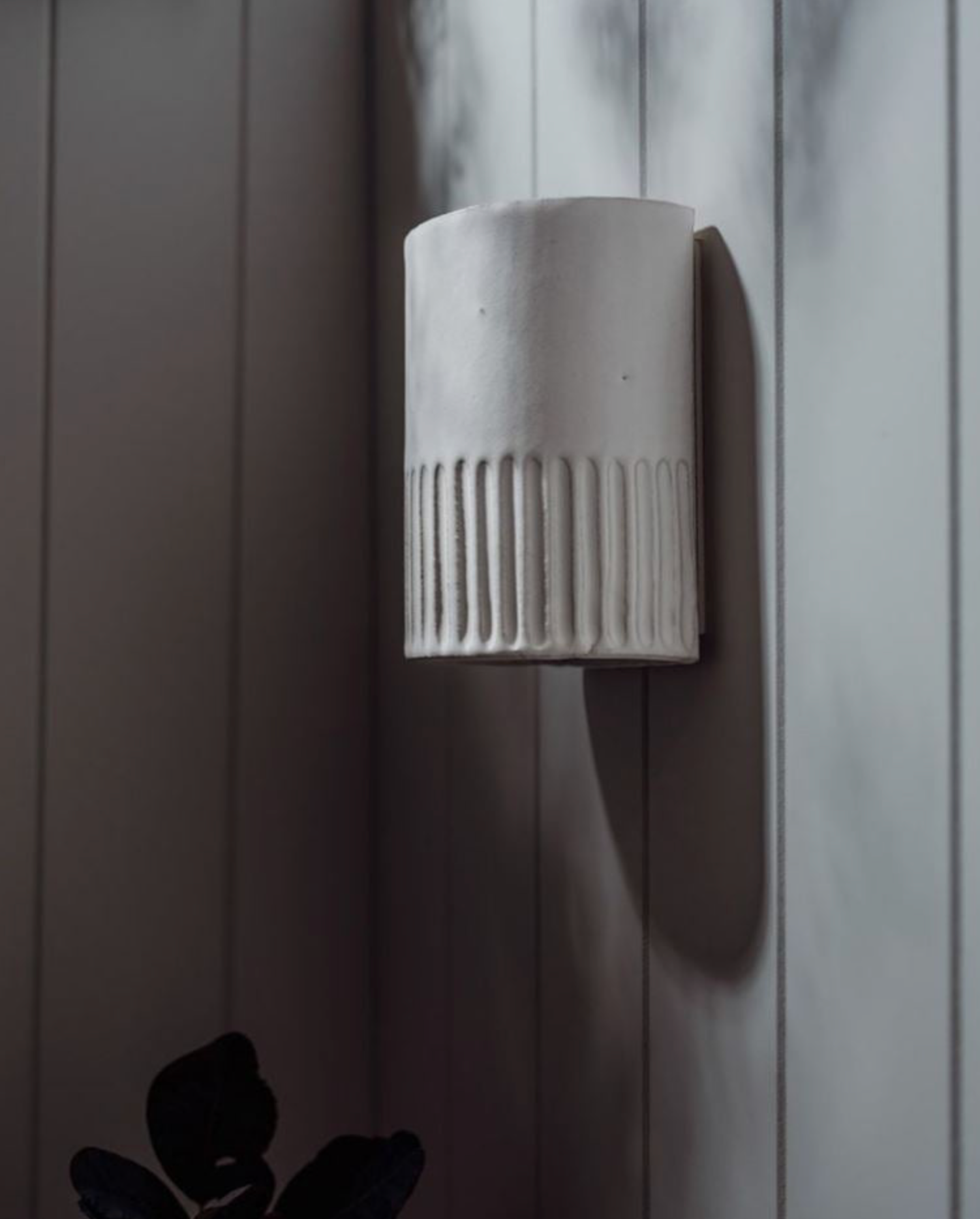 Ceramic wall sconce with textured design on a neutral background