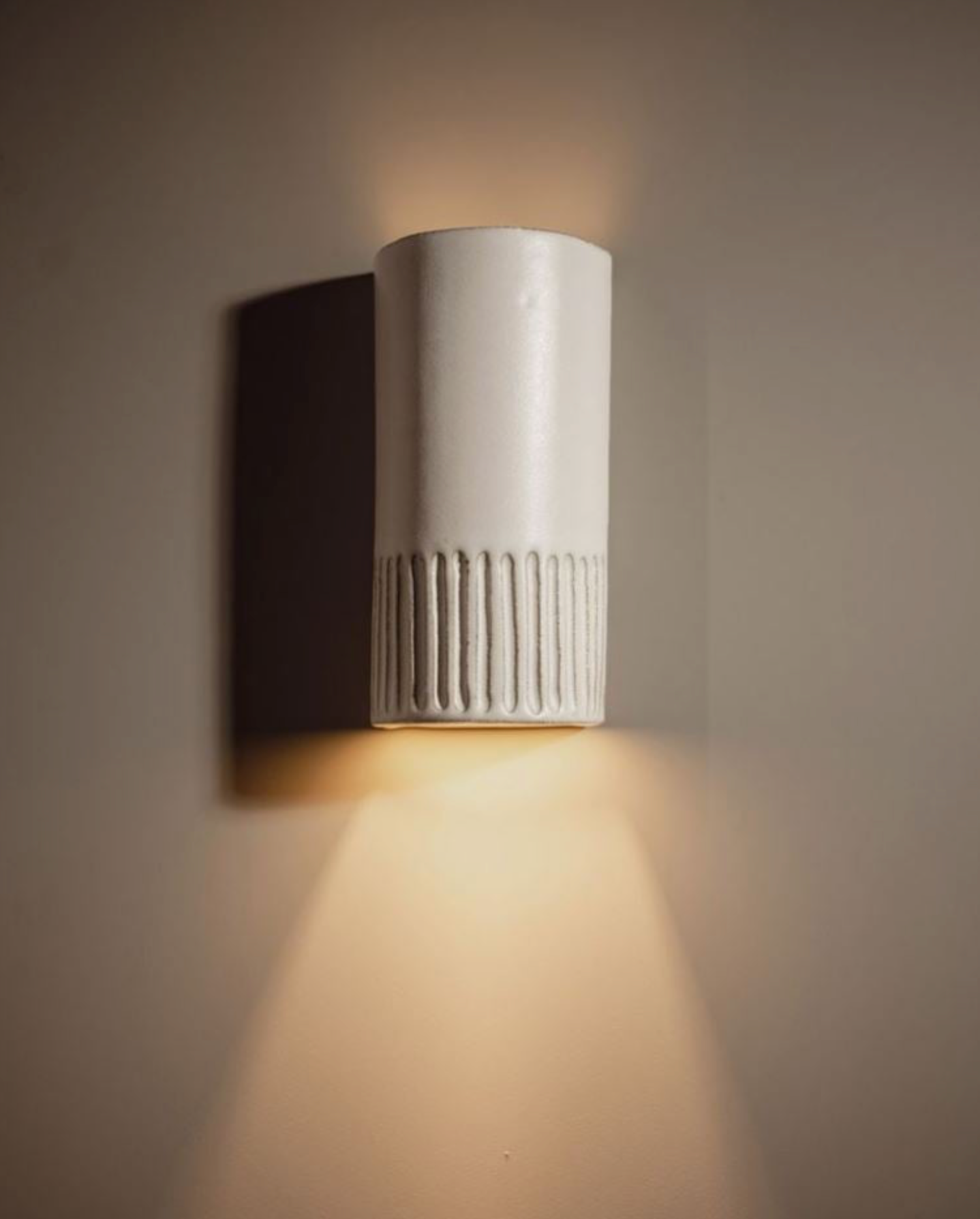 White ceramic wall-mounted light fixture on a beige wall