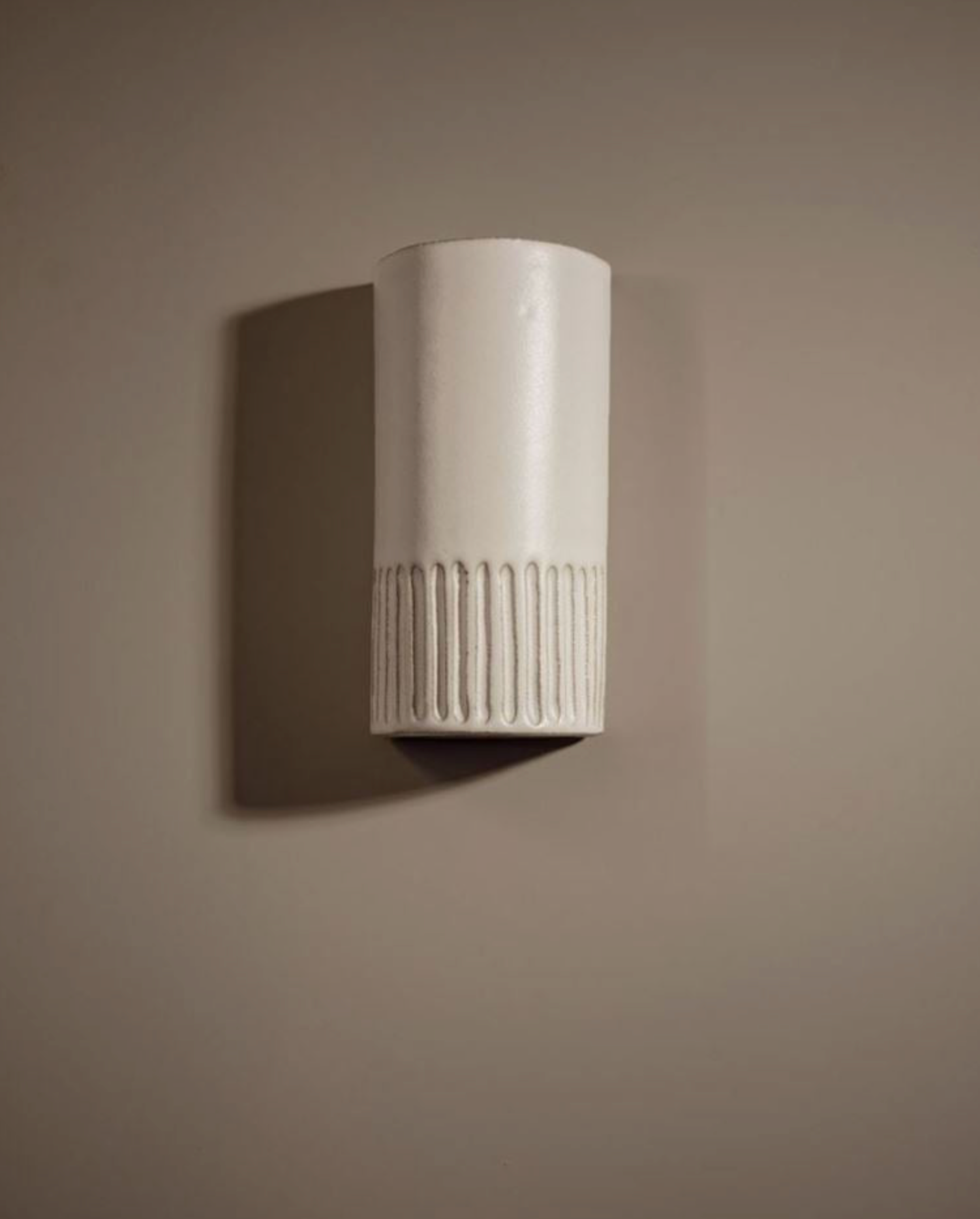 White ceramic interior wall sconce on a beige wall