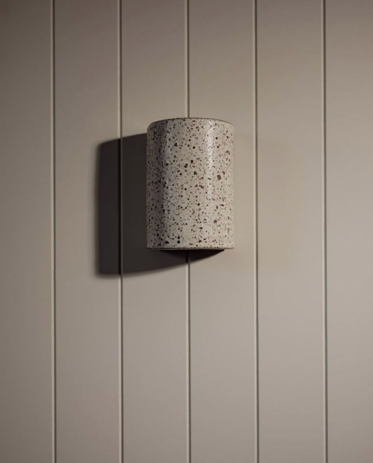 Cylindrical wall light fixture on a paneled wall