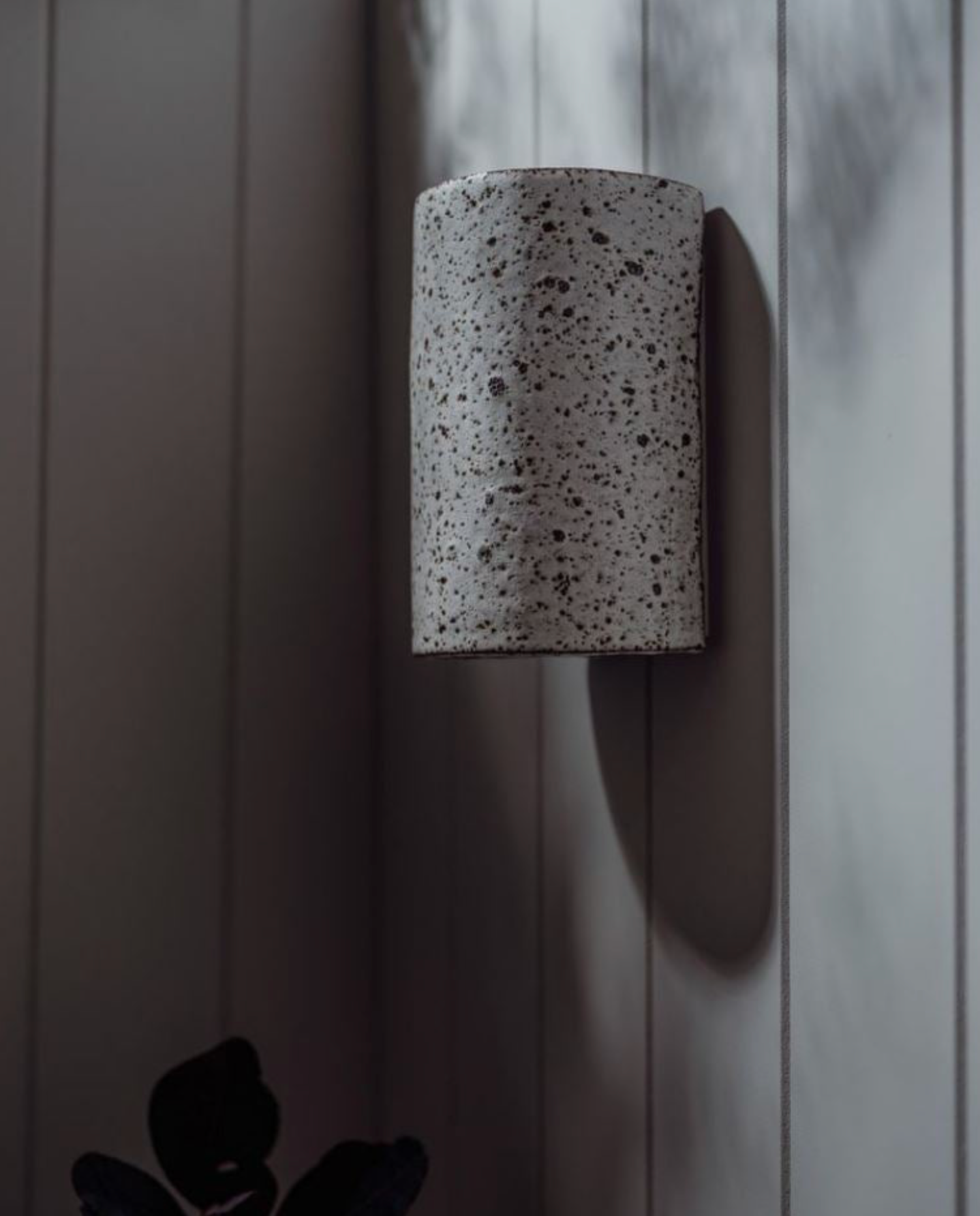 Cylindrical ceramic wall sconce on a textured wall
