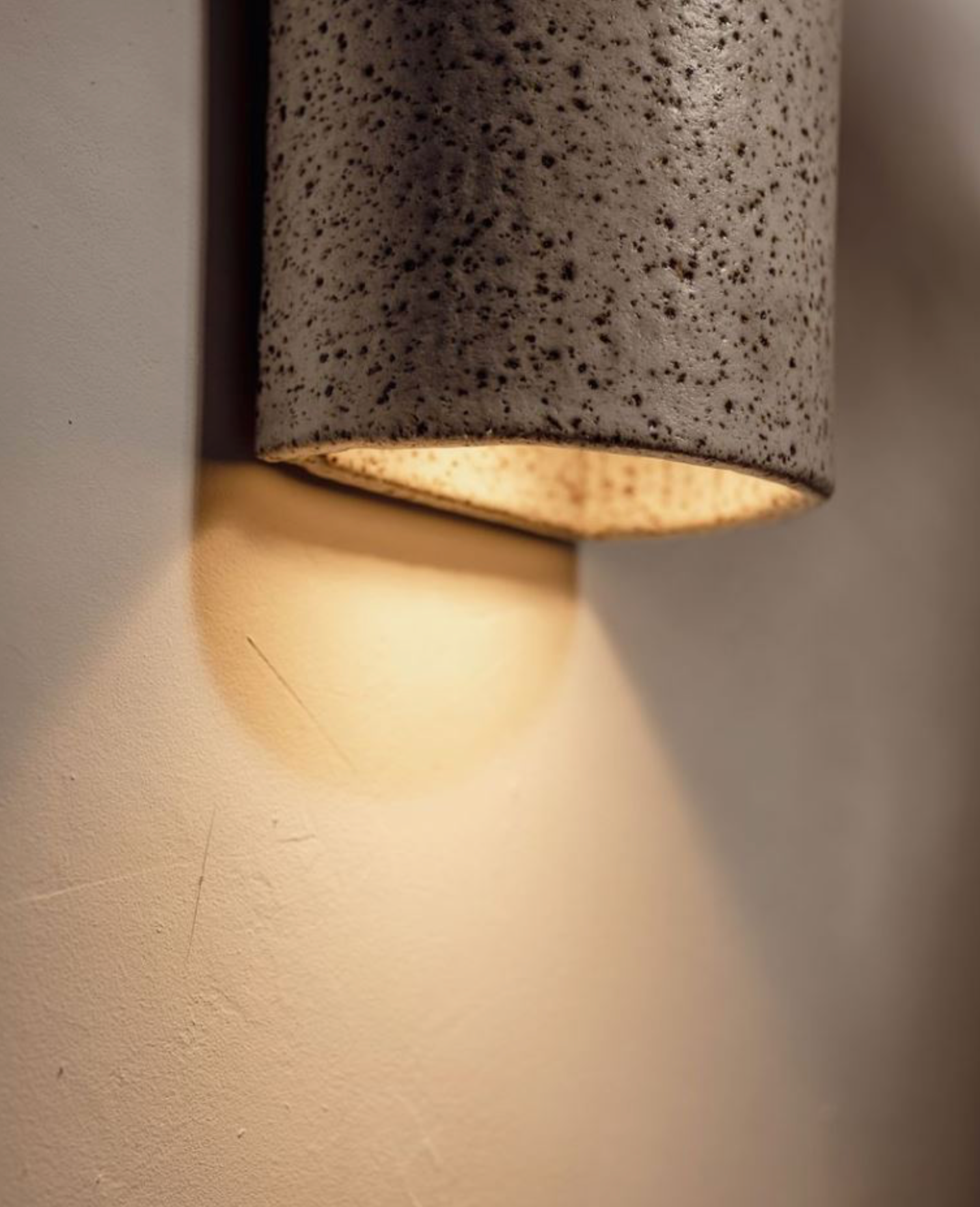 Cylindrical wall light fixture with textured surface on a neutral wall.
