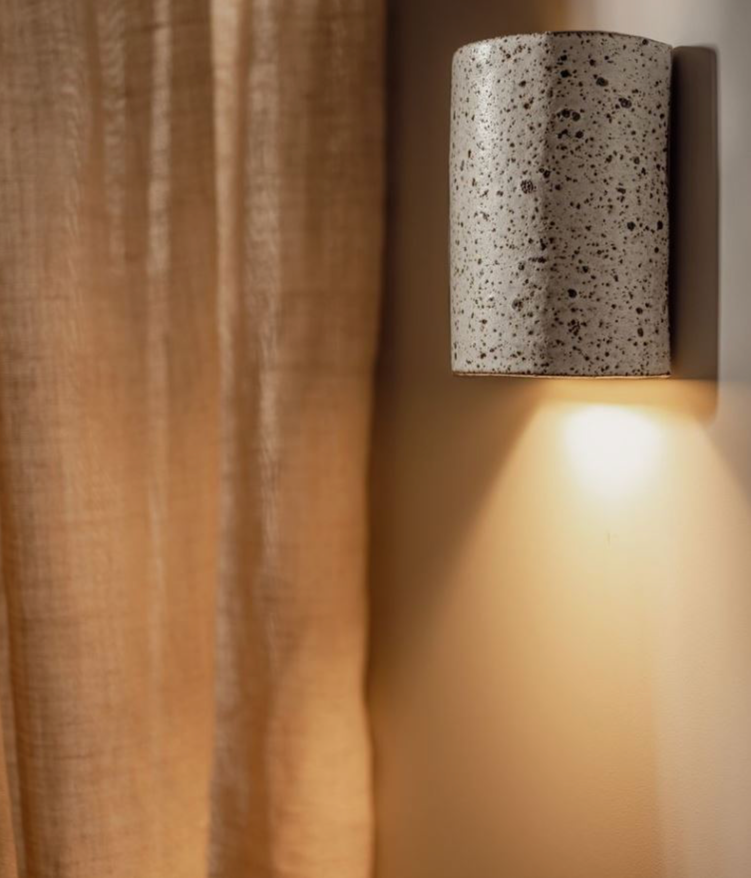 Cylindrical wall light fixture on a textured wall with soft lighting.